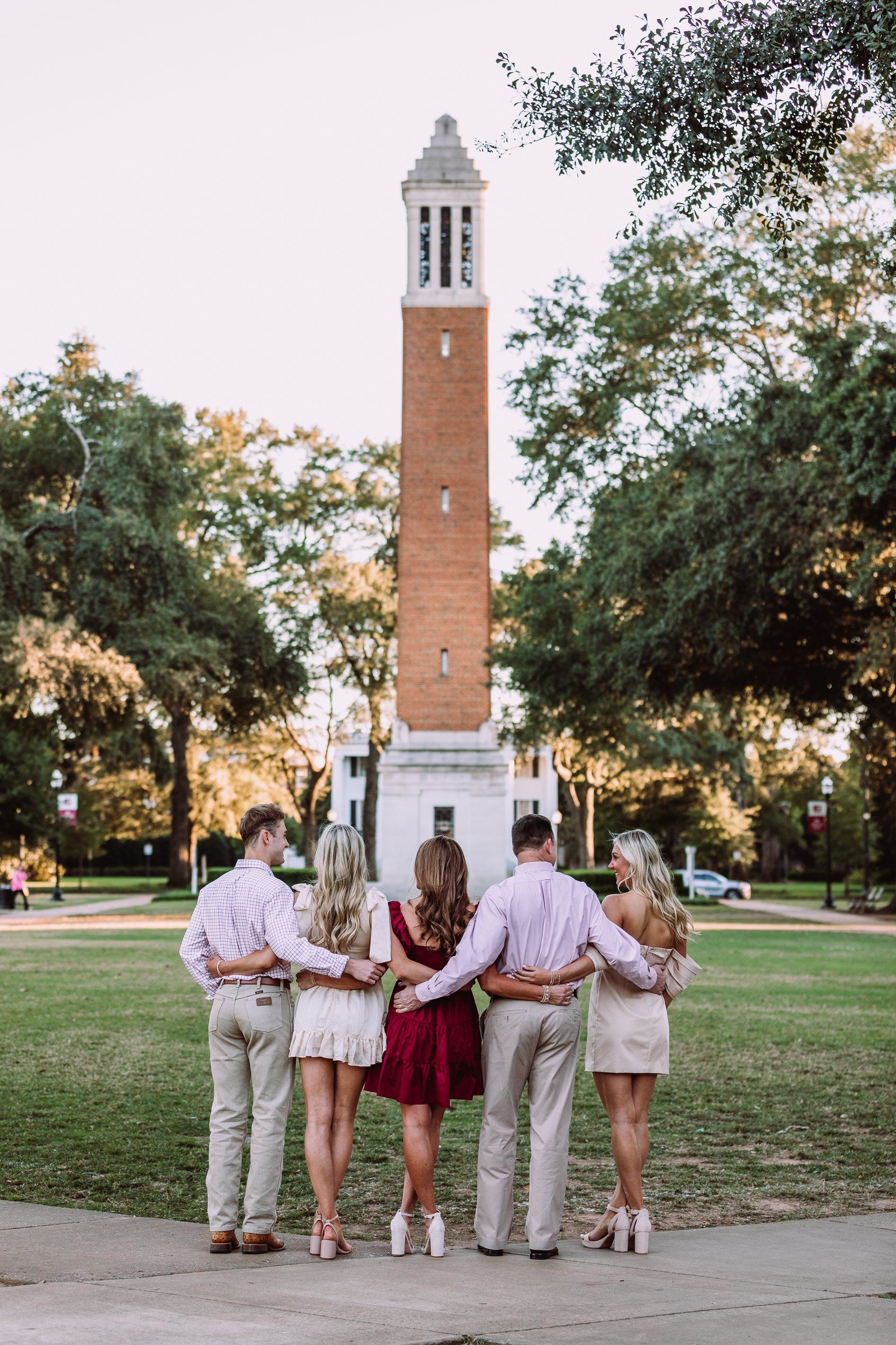 A group of people are standing in front of a clock tower.