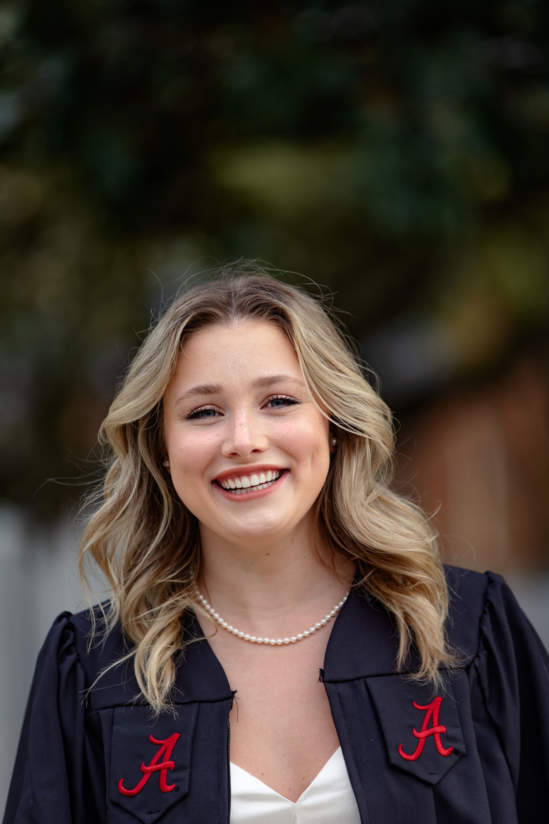 A woman in a graduation cap and gown is smiling for the camera.