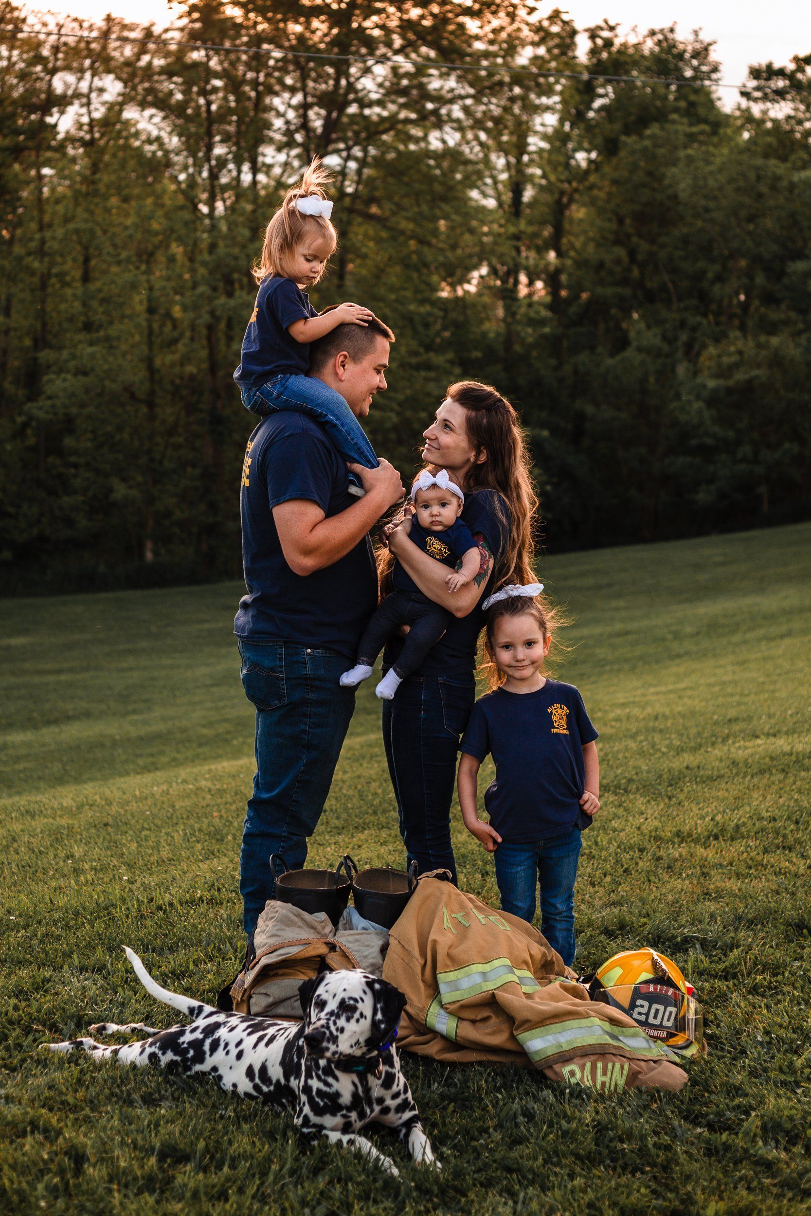 A family is posing for a picture in a field with a dalmatian dog.