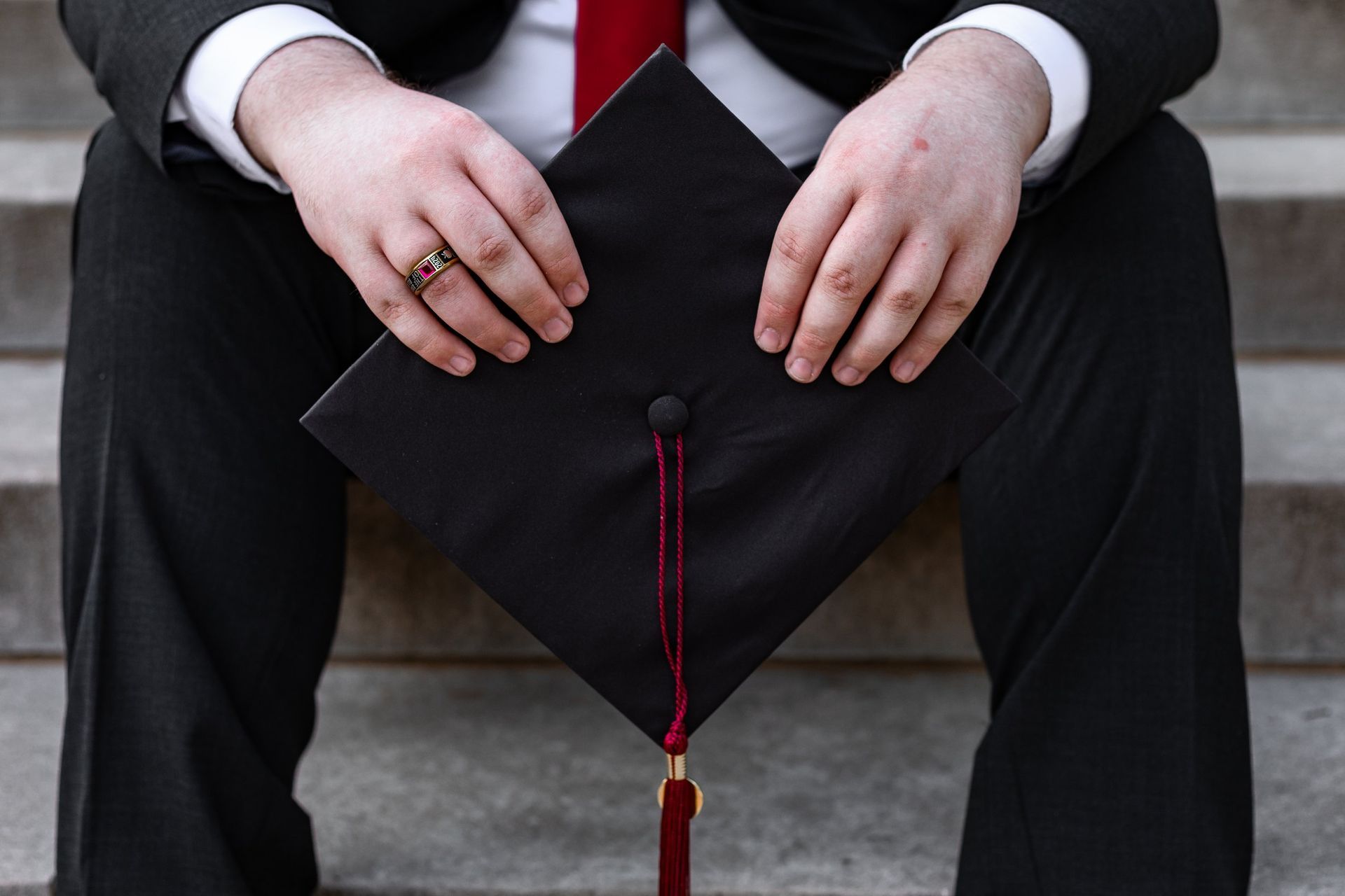 A man in a suit and tie is holding a graduation cap