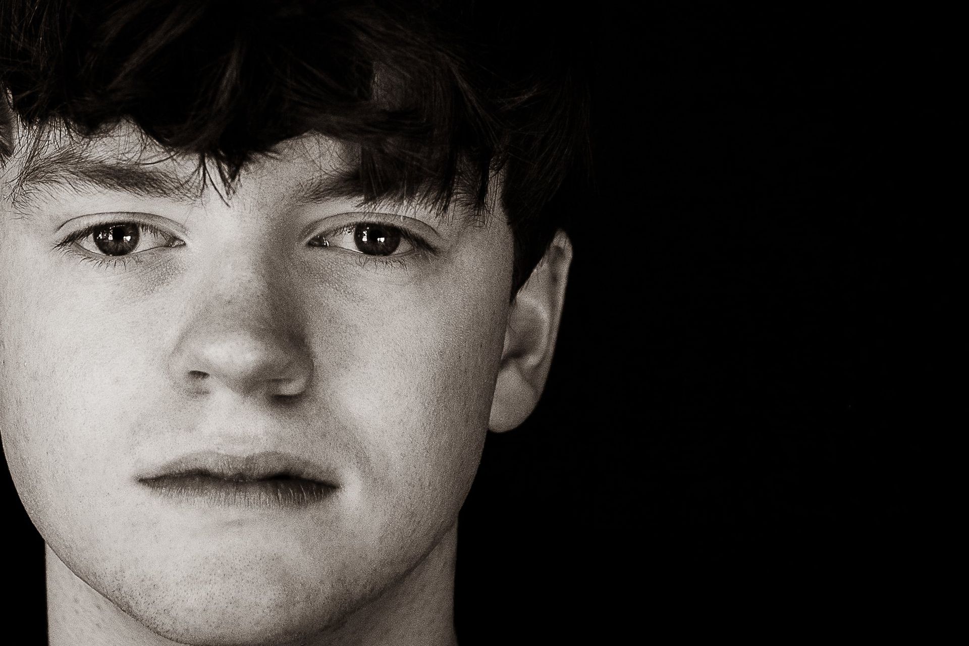 A close up of a young man 's face in a black and white photo.