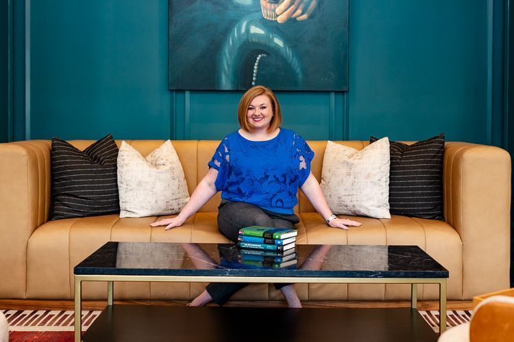A woman is sitting on a couch next to a coffee table.