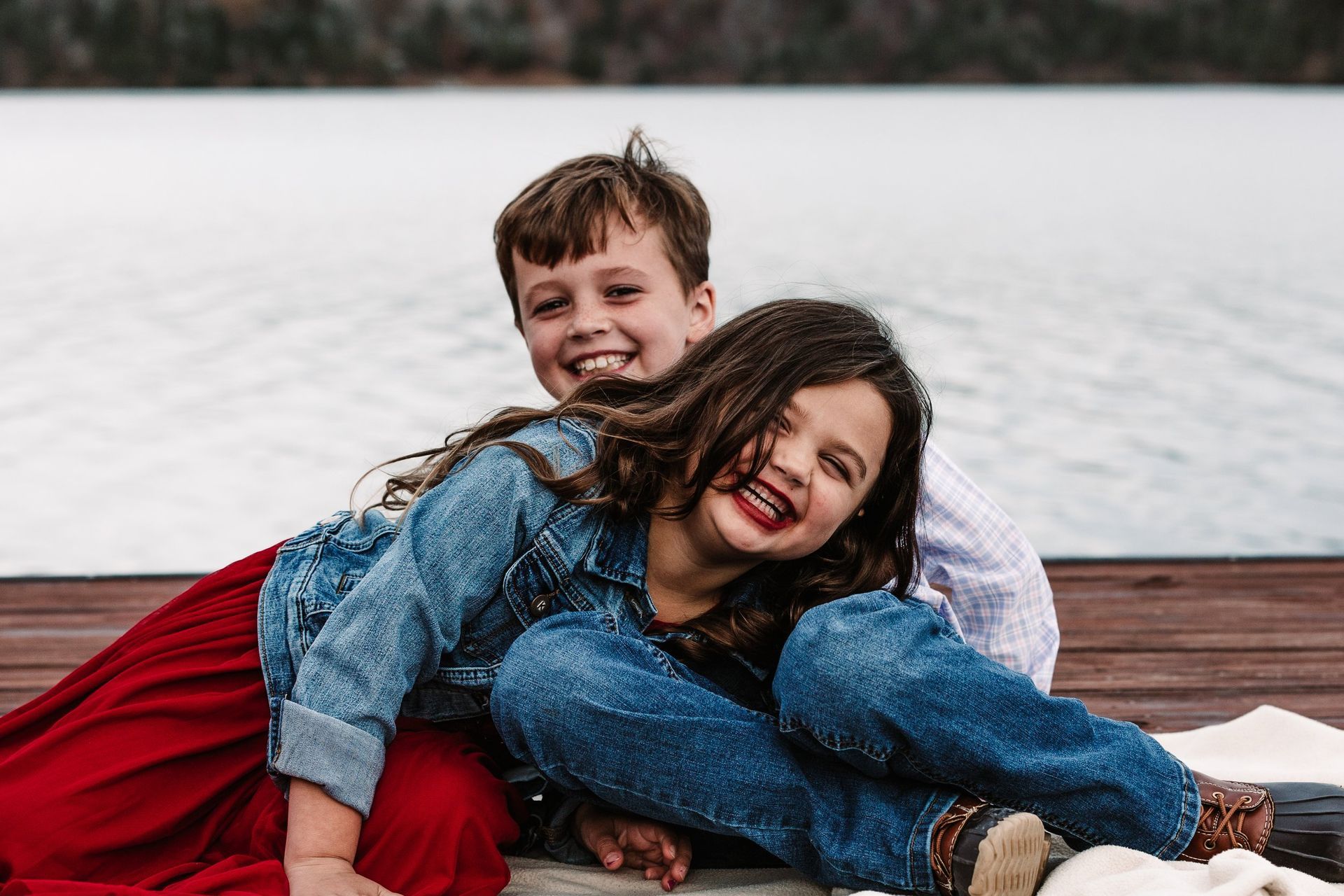 A boy and a girl are sitting next to each other on a dock.