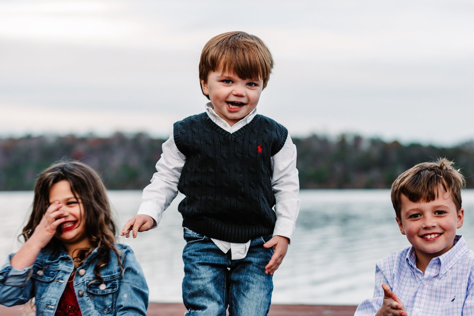 A boy and two girls are standing next to each other on a dock.