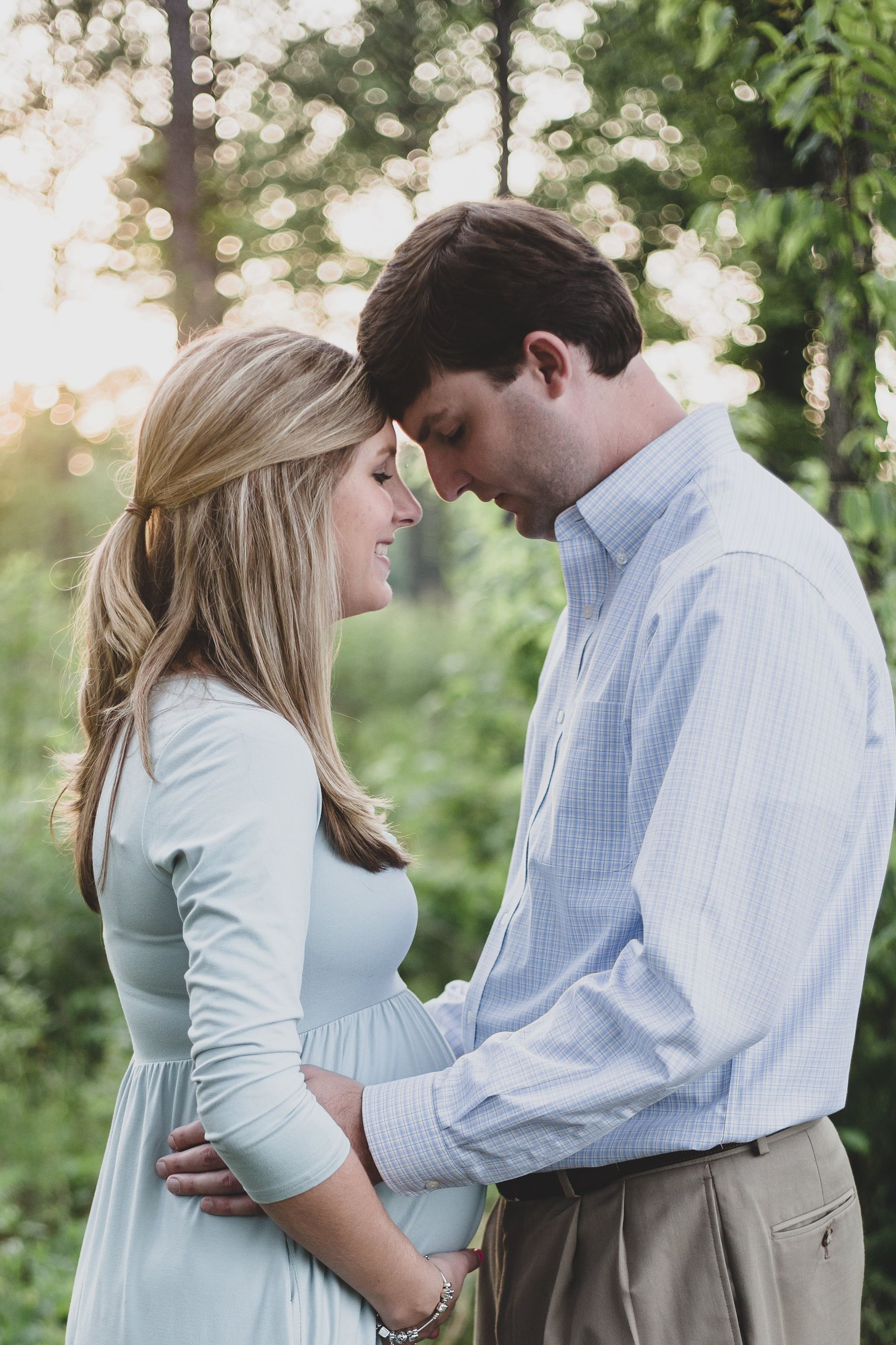 A man and a pregnant woman are looking at each other in the woods.