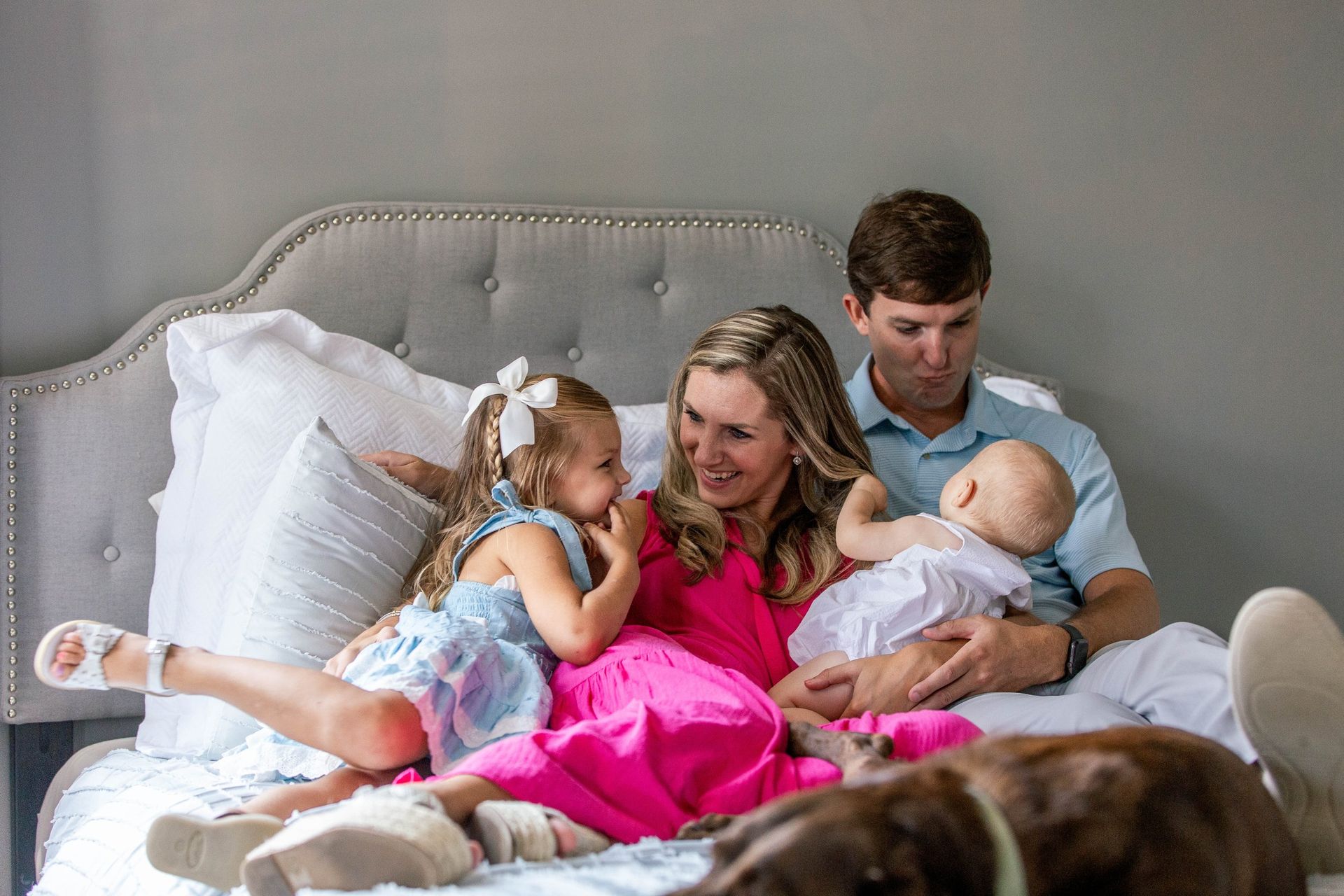 A family is sitting on a bed with a dog.