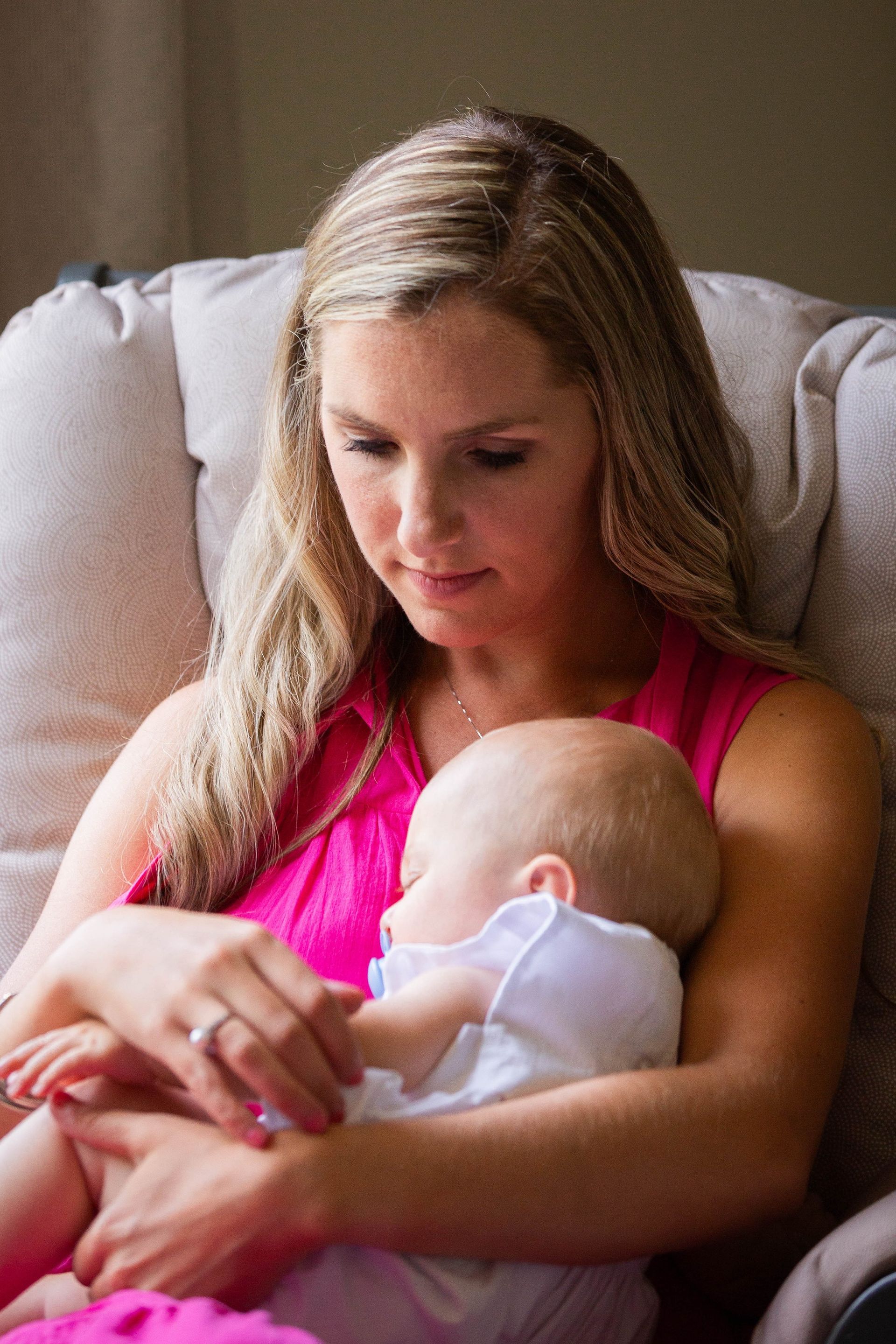 A woman is holding a baby in her arms while sitting in a chair.
