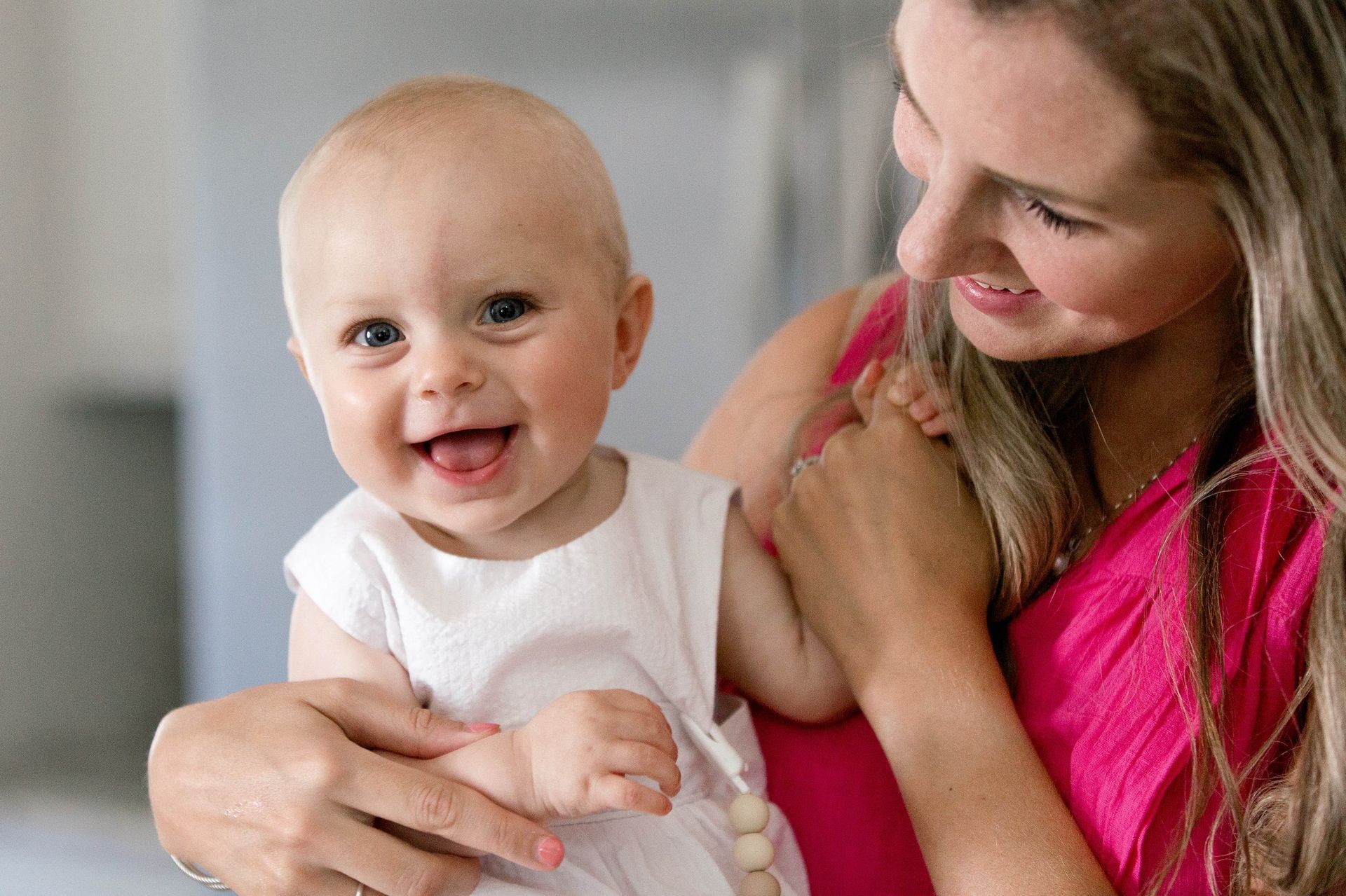 A woman is holding a baby in her arms and the baby is smiling.