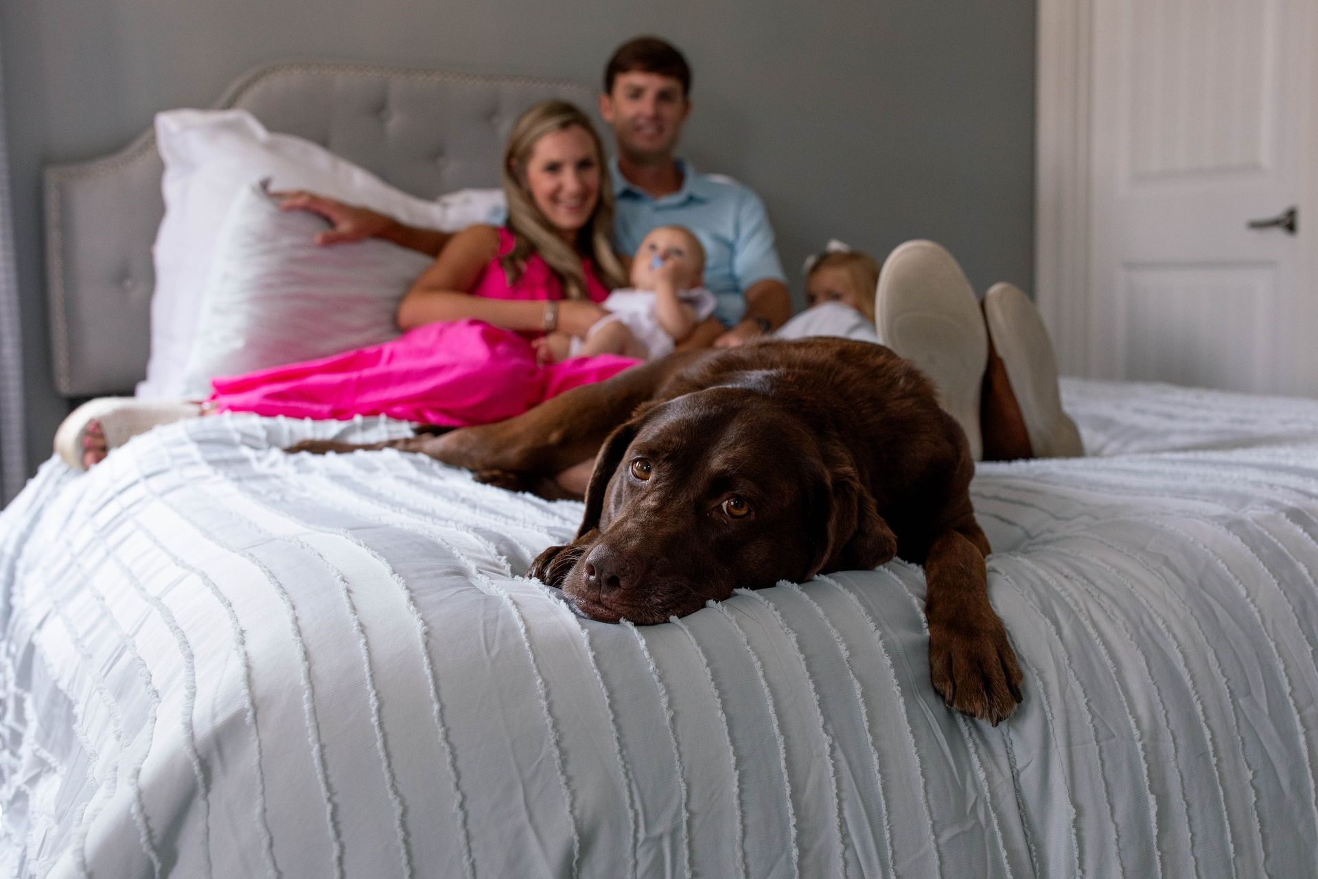 A family is laying on a bed with a dog.