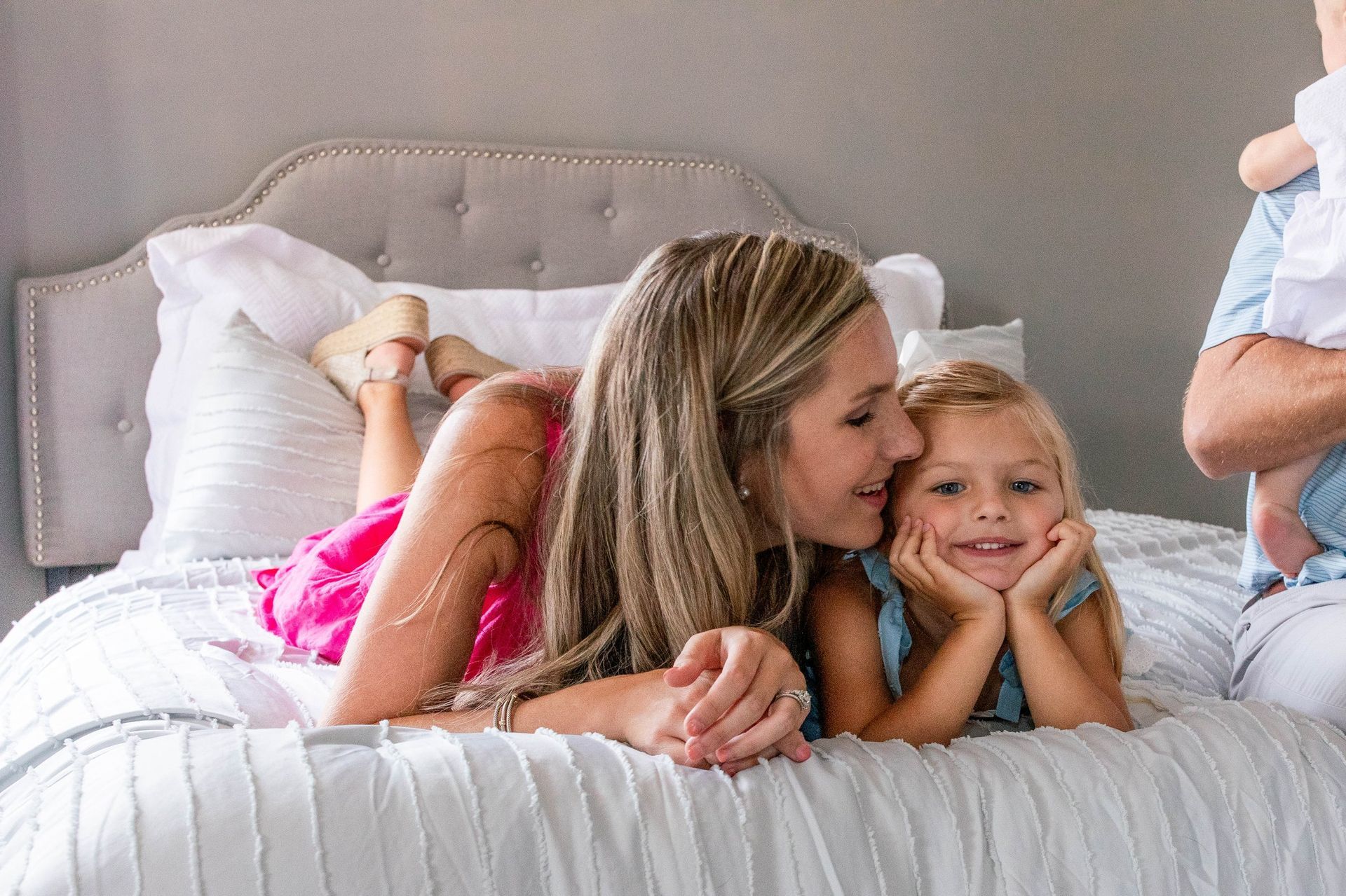 A woman and two children are laying on a bed.