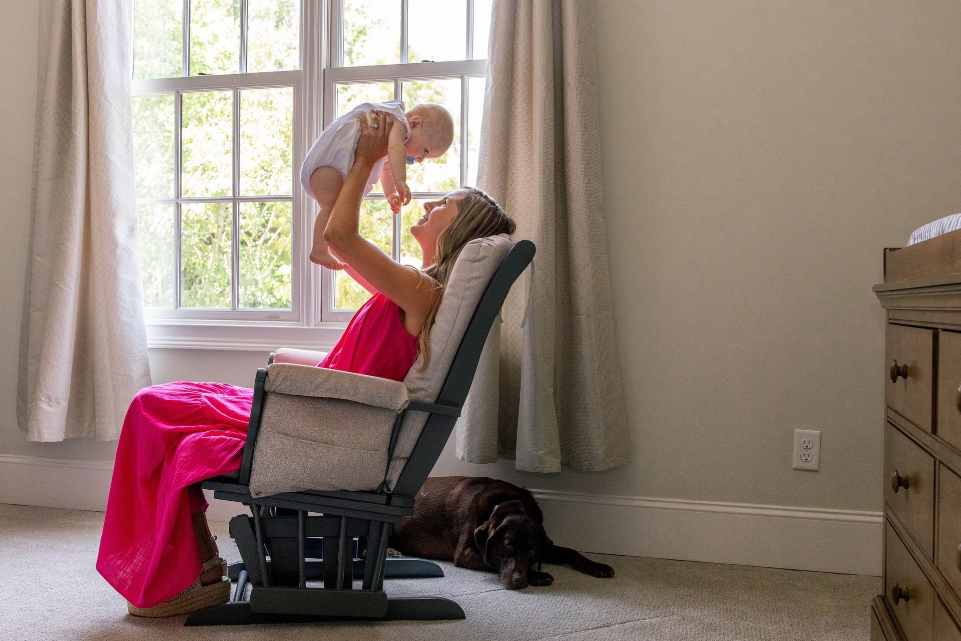A woman is sitting in a rocking chair holding a baby in her arms.