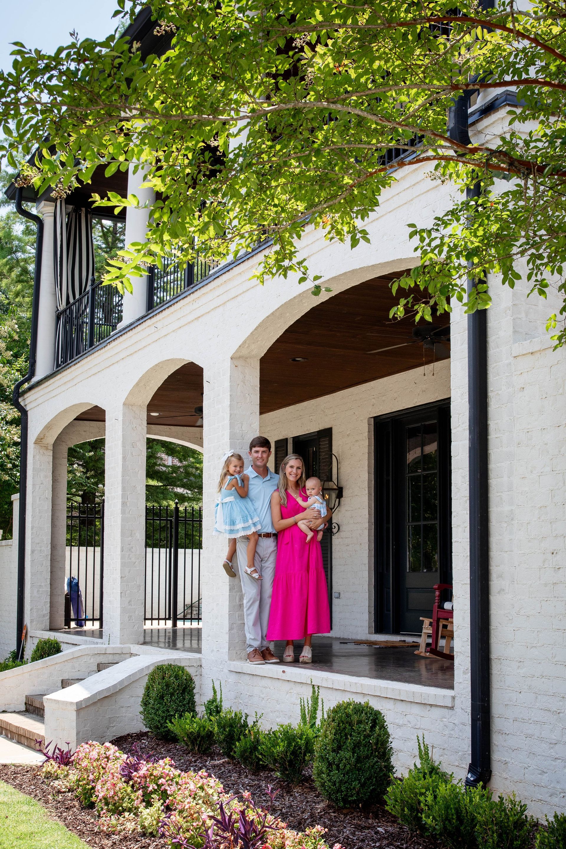 A family is standing on the porch of their house.