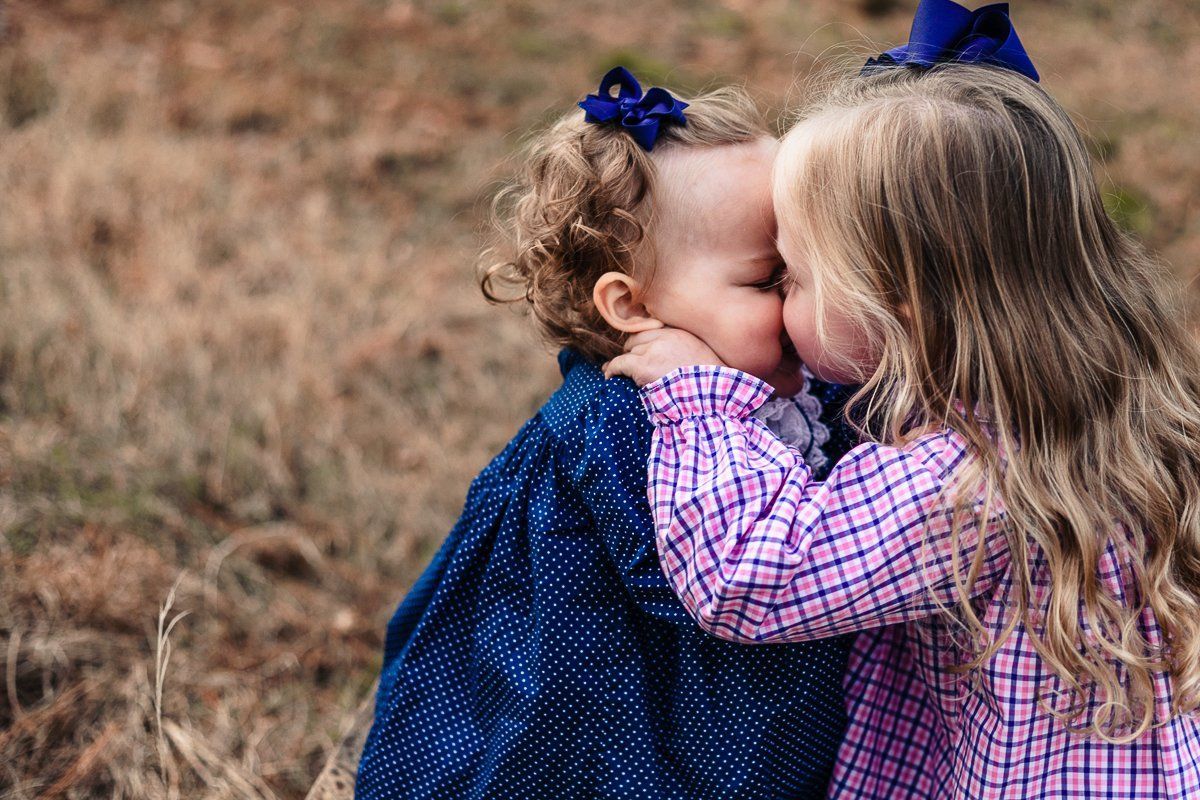 Two girls in a field sharing a moment.