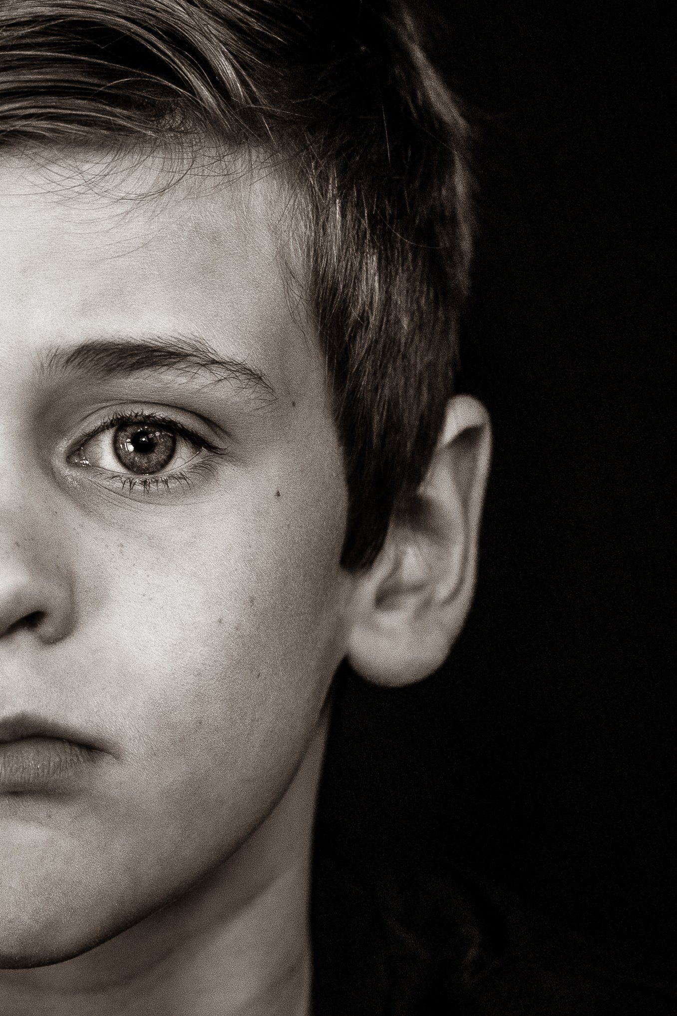 A close up of a young boy 's face in a black and white photo.