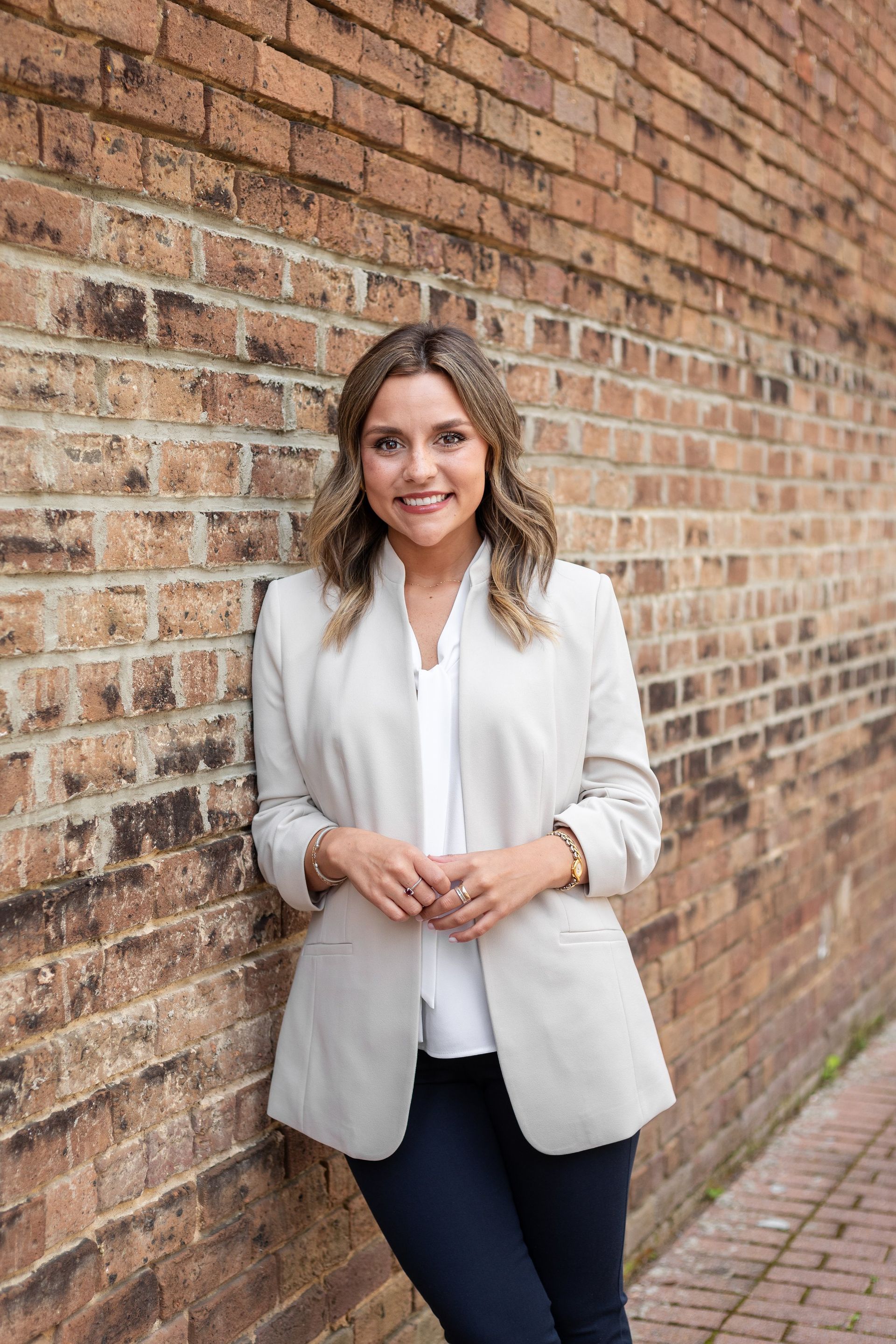 A woman is standing in front of a brick wall.