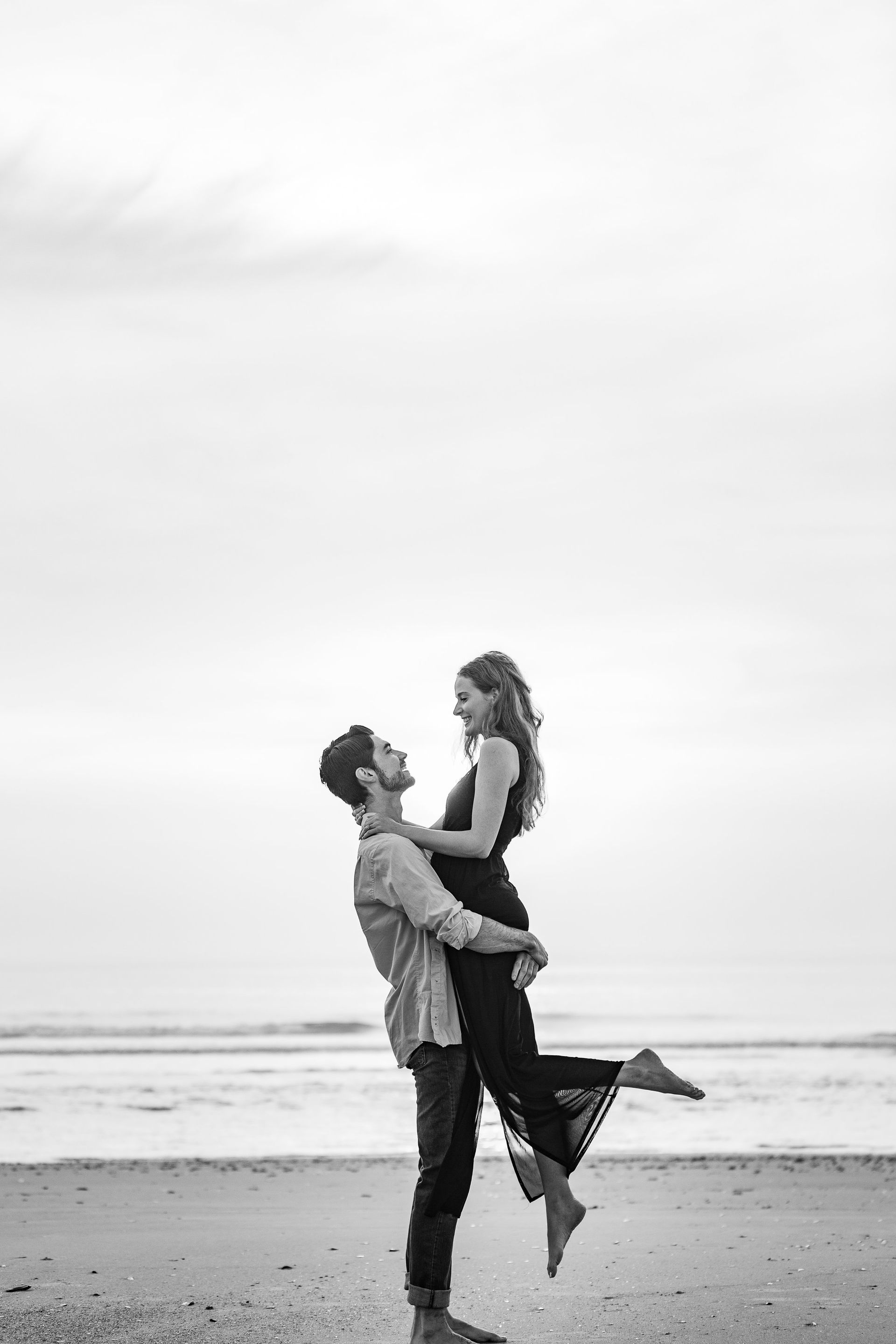 A man is holding a woman in his arms on the beach.