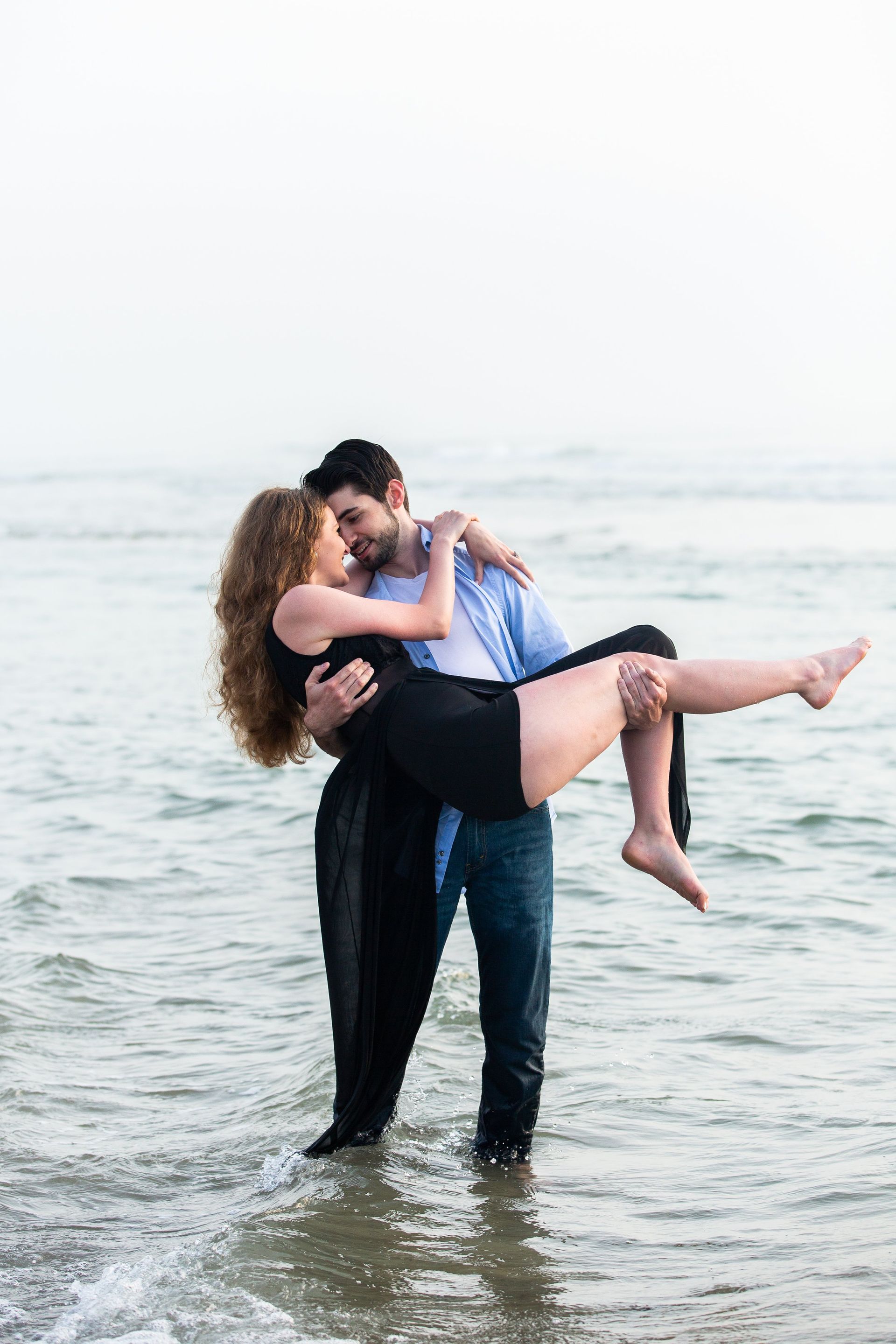 A man is holding a woman in his arms in the water.