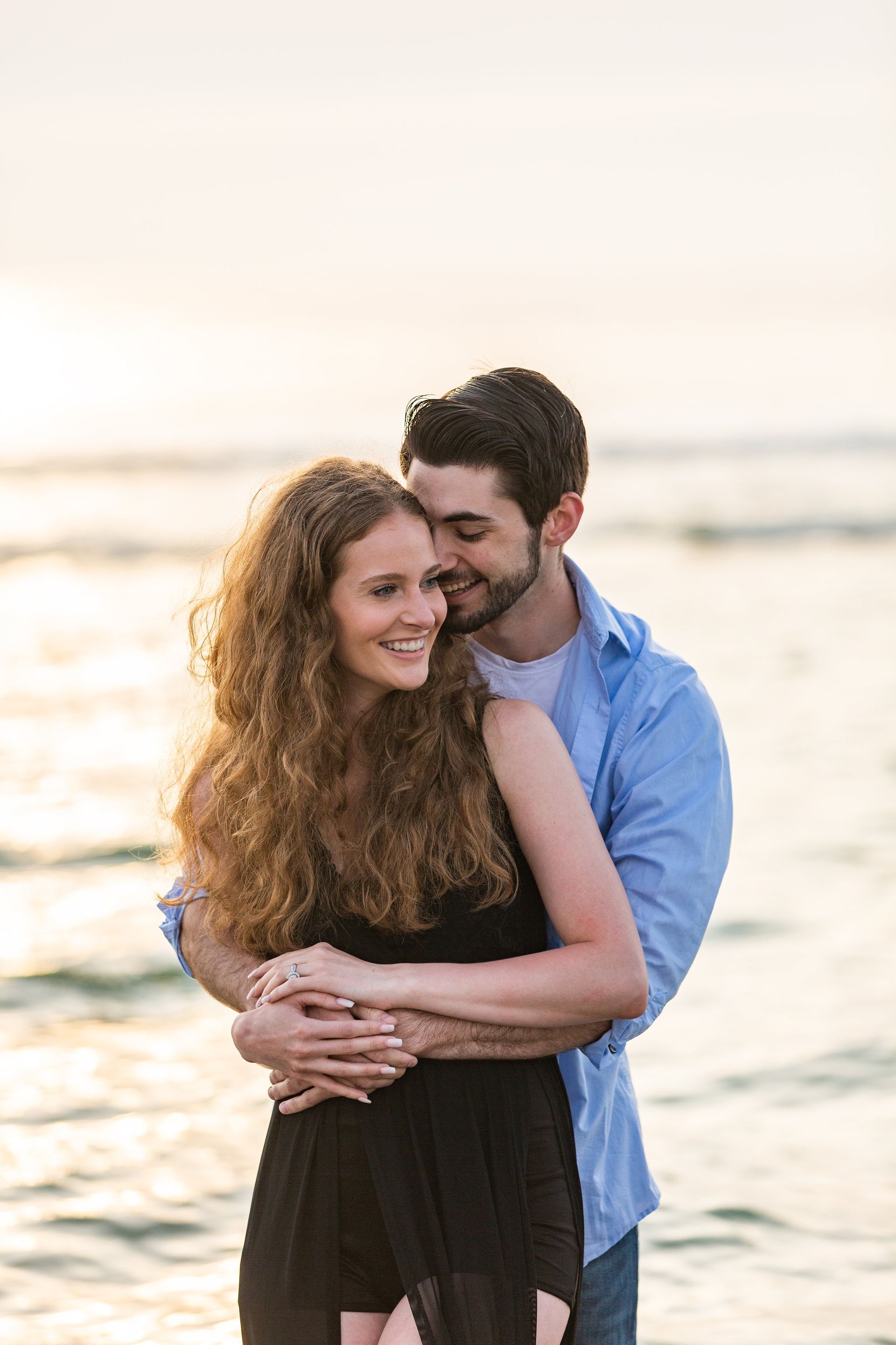 A man and a woman are hugging each other on the beach.