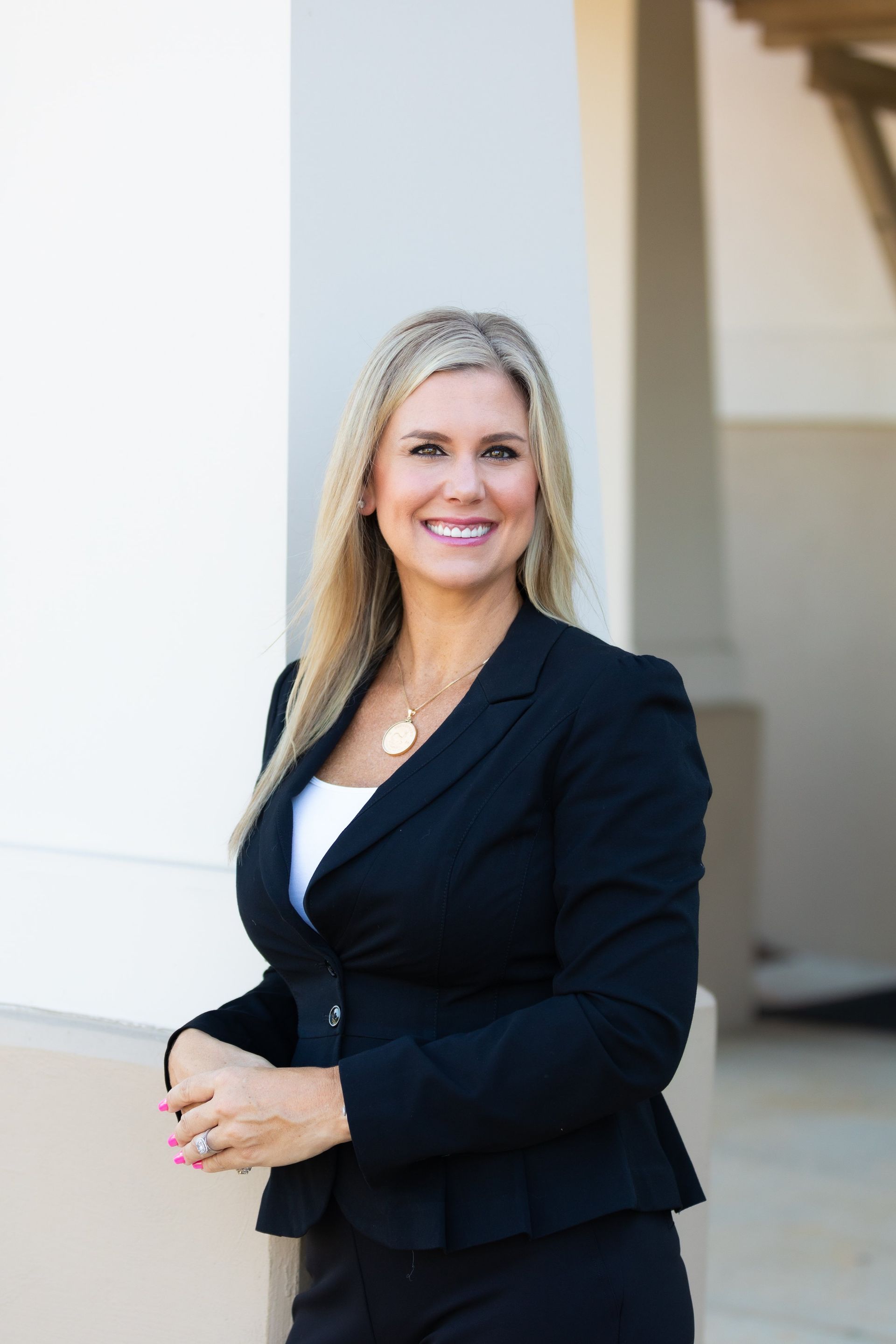 A woman in a black suit is standing in front of a building.