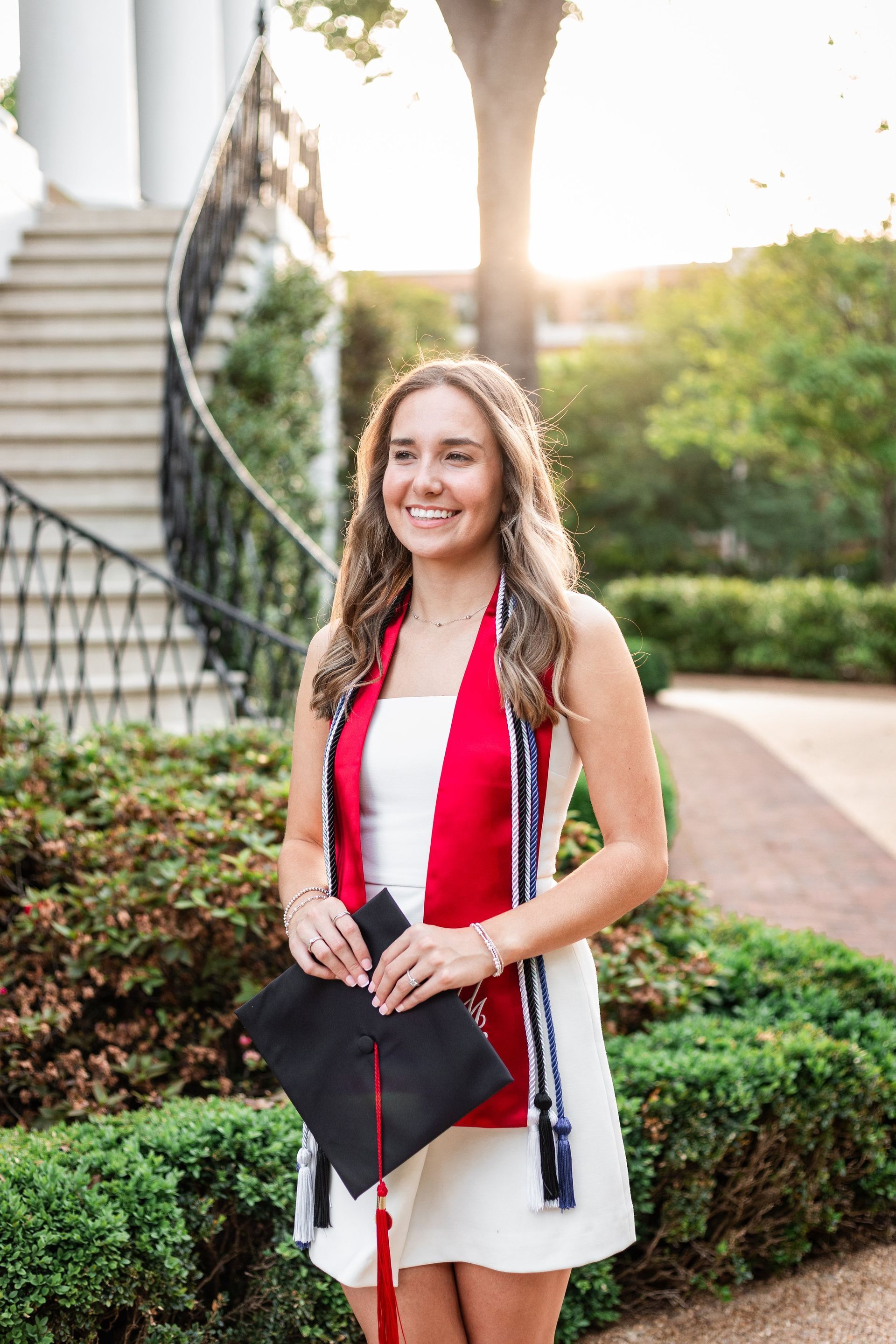 A woman is wearing a graduation cap and gown and holding a diploma.