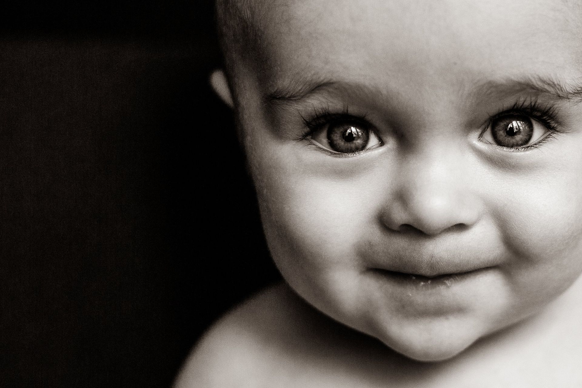 A baby is smiling in a black and white photo.