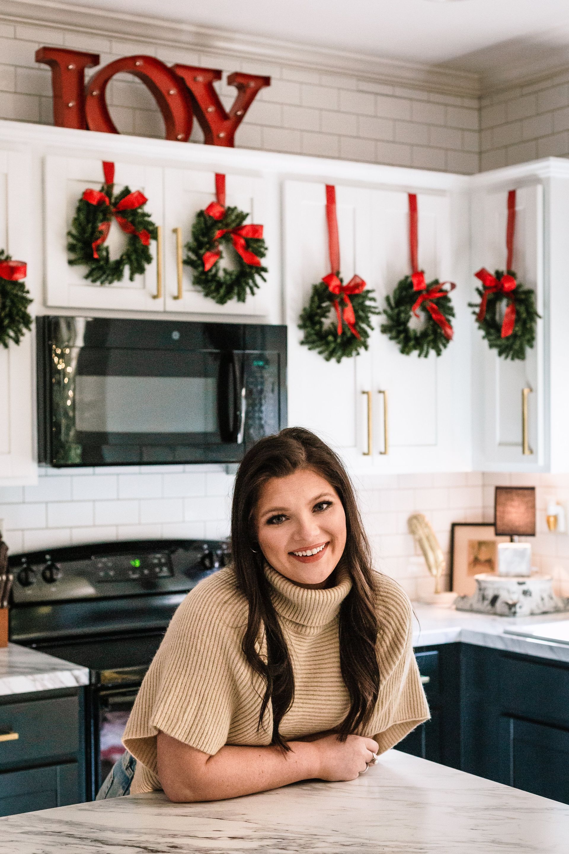 A woman is sitting at a counter in a kitchen decorated for christmas.