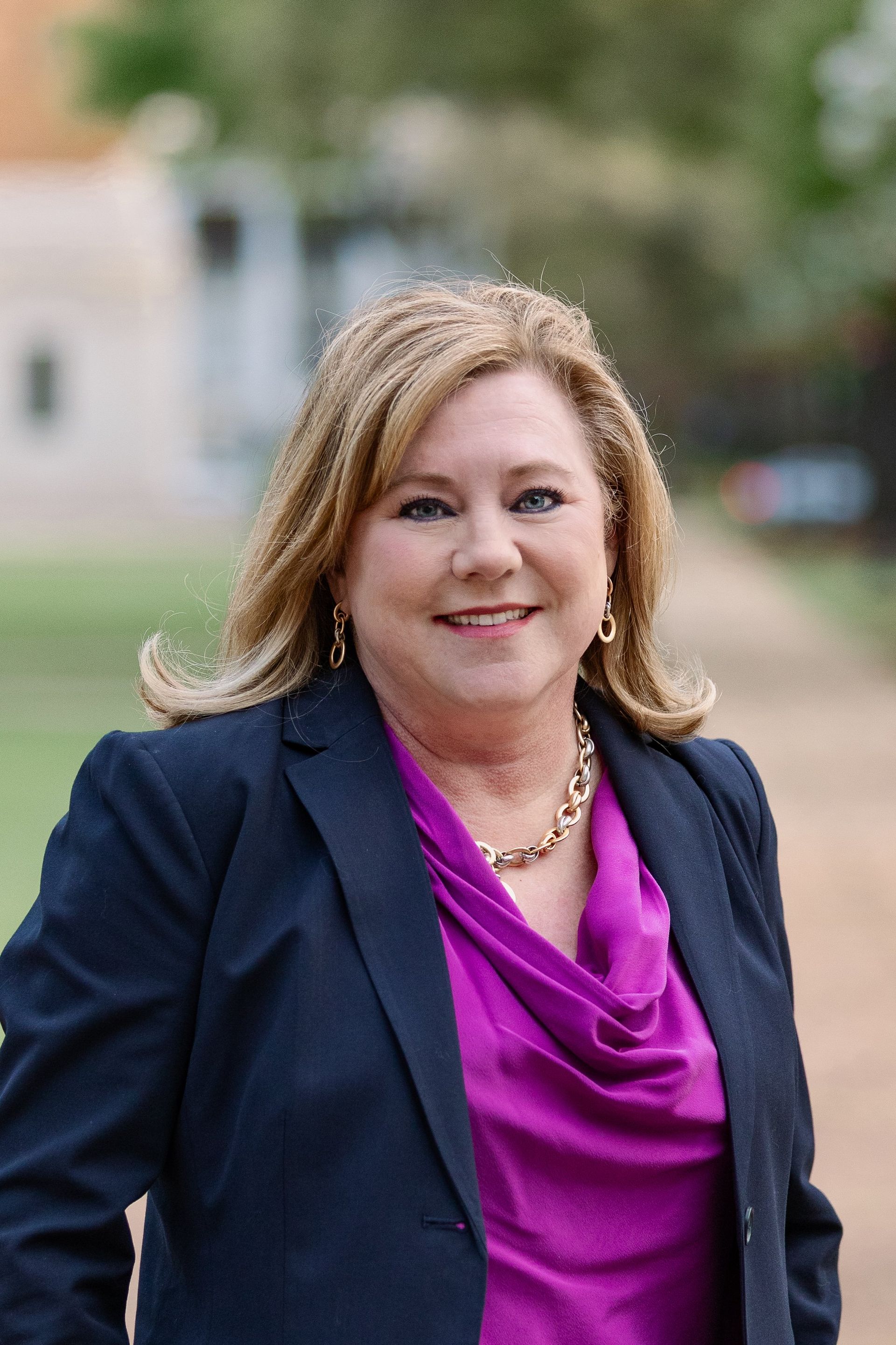 A woman in a blue jacket and purple shirt is smiling for the camera.