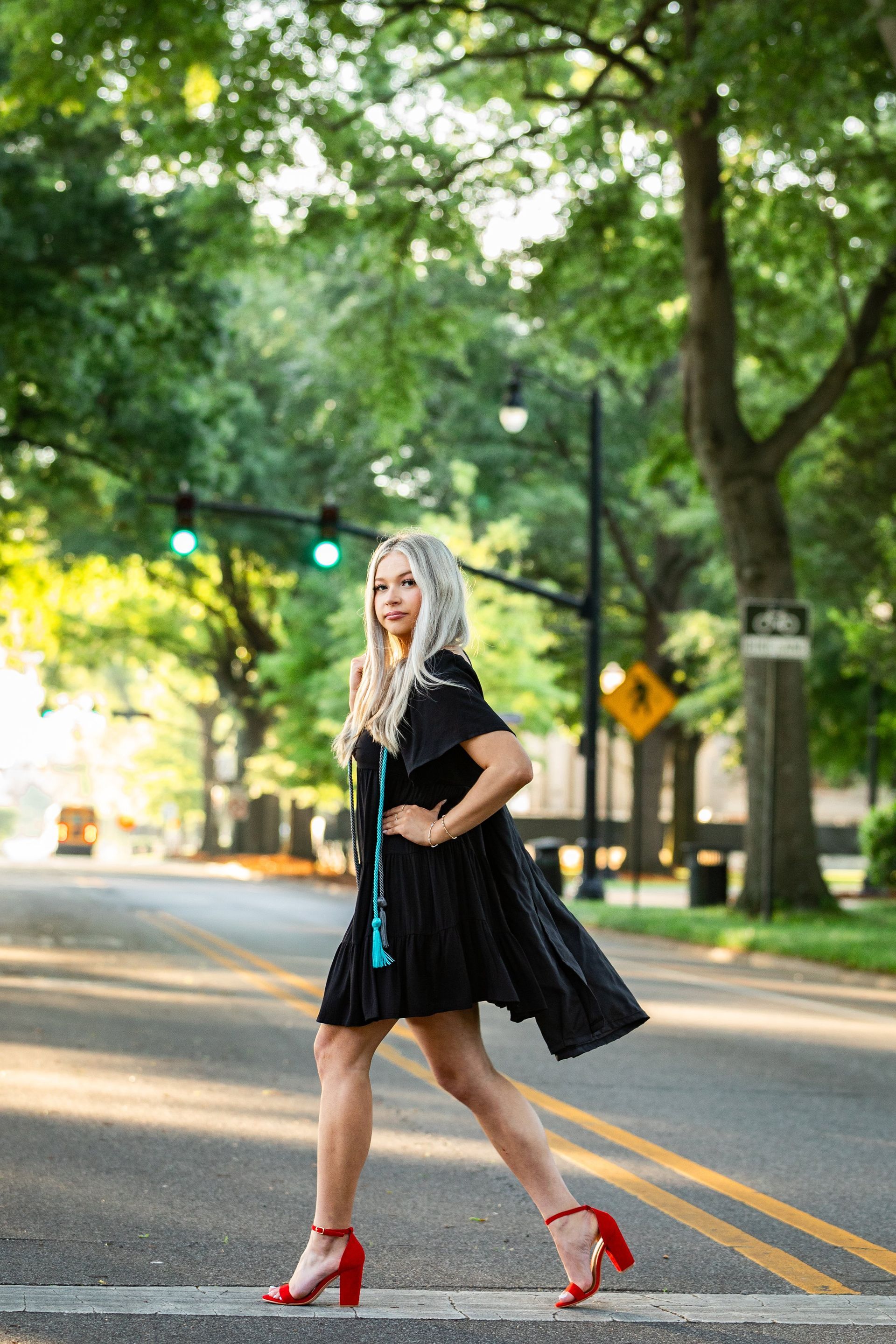 A woman in a black dress and red heels is crossing the street.