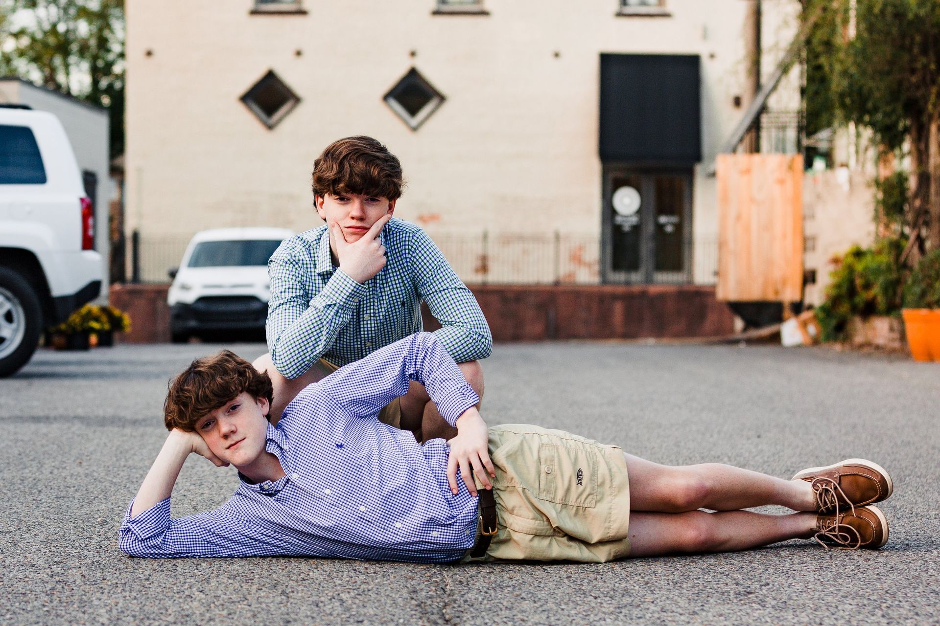 Two young men are laying on the ground in front of a building.