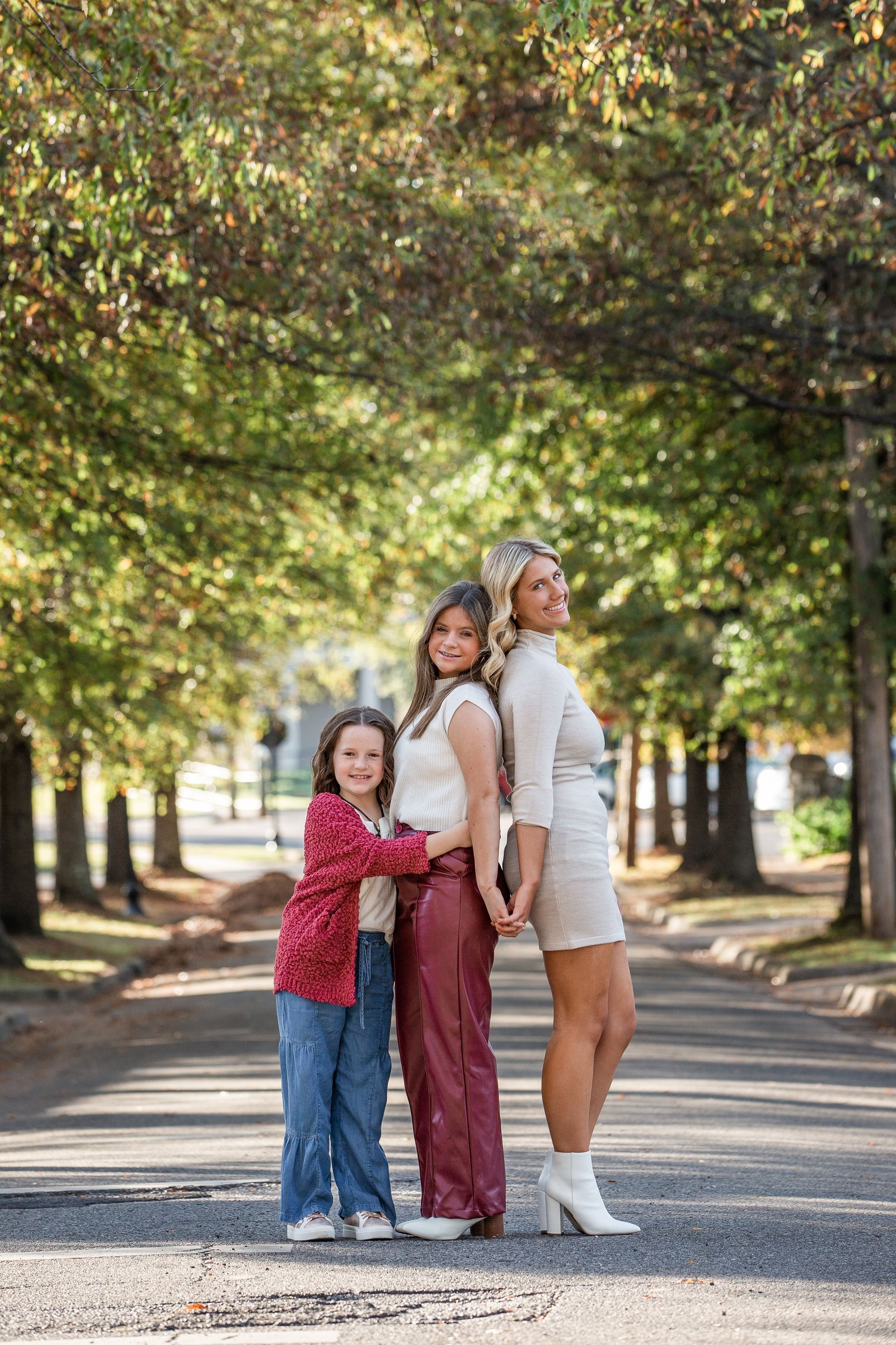 A woman and two children are standing next to each other on a sidewalk holding hands.