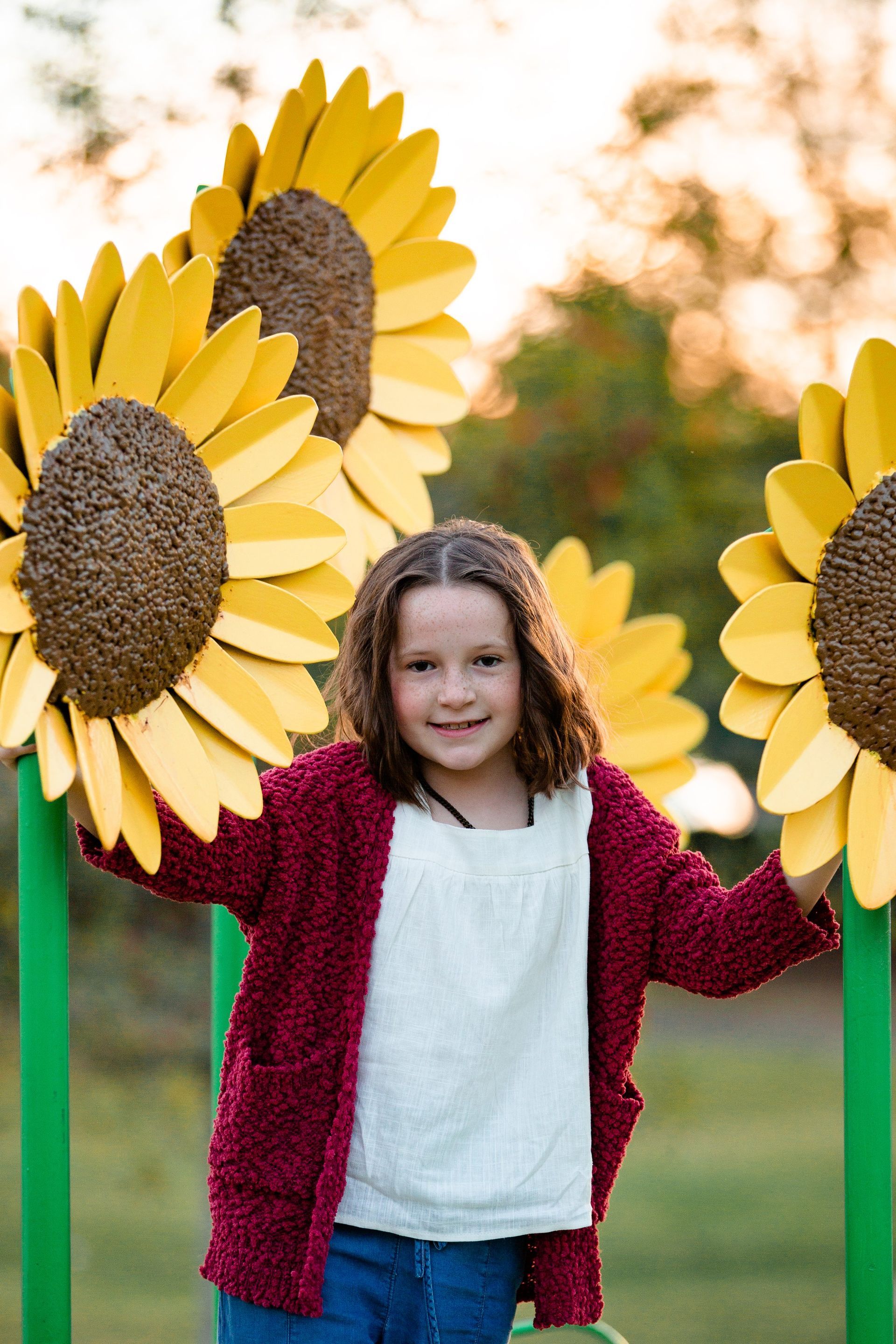 A little girl is standing in front of a row of sunflowers.