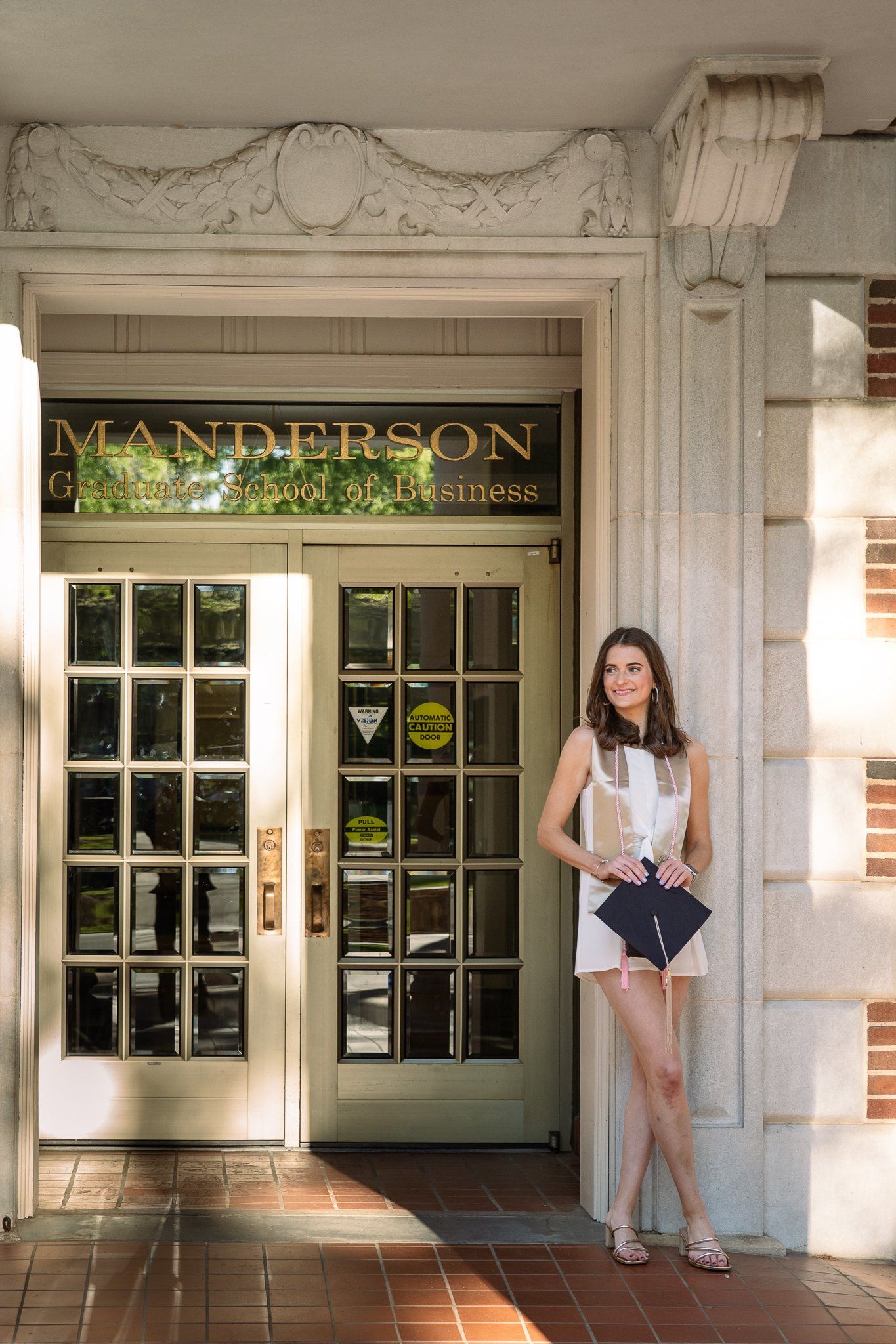 A woman in a white dress is standing in front of a building.