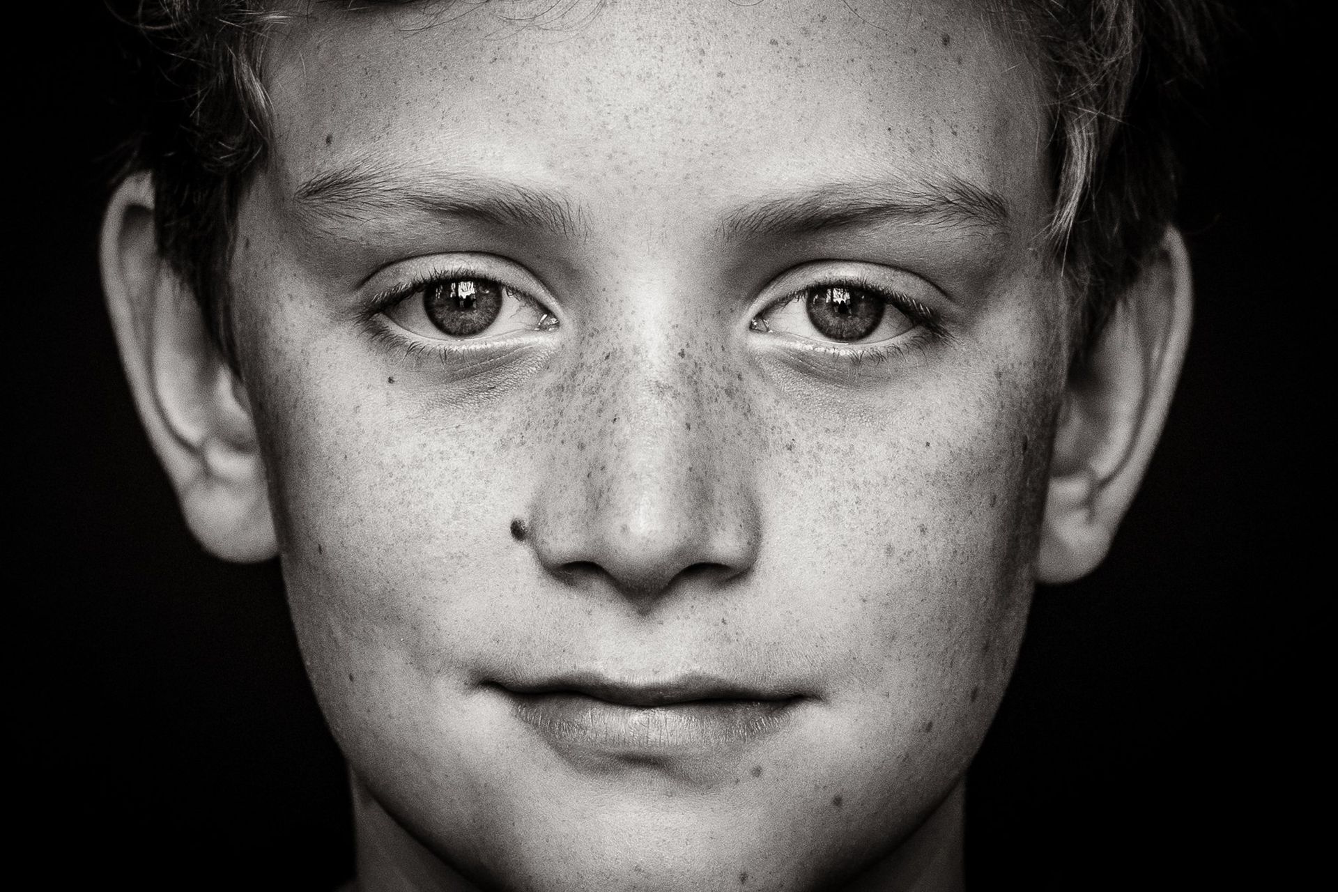 A black and white photo of a young boy with freckles on his face.