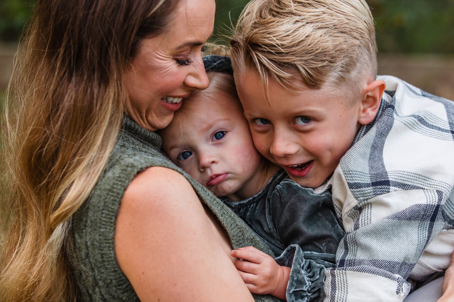 A woman is holding two children in her arms.