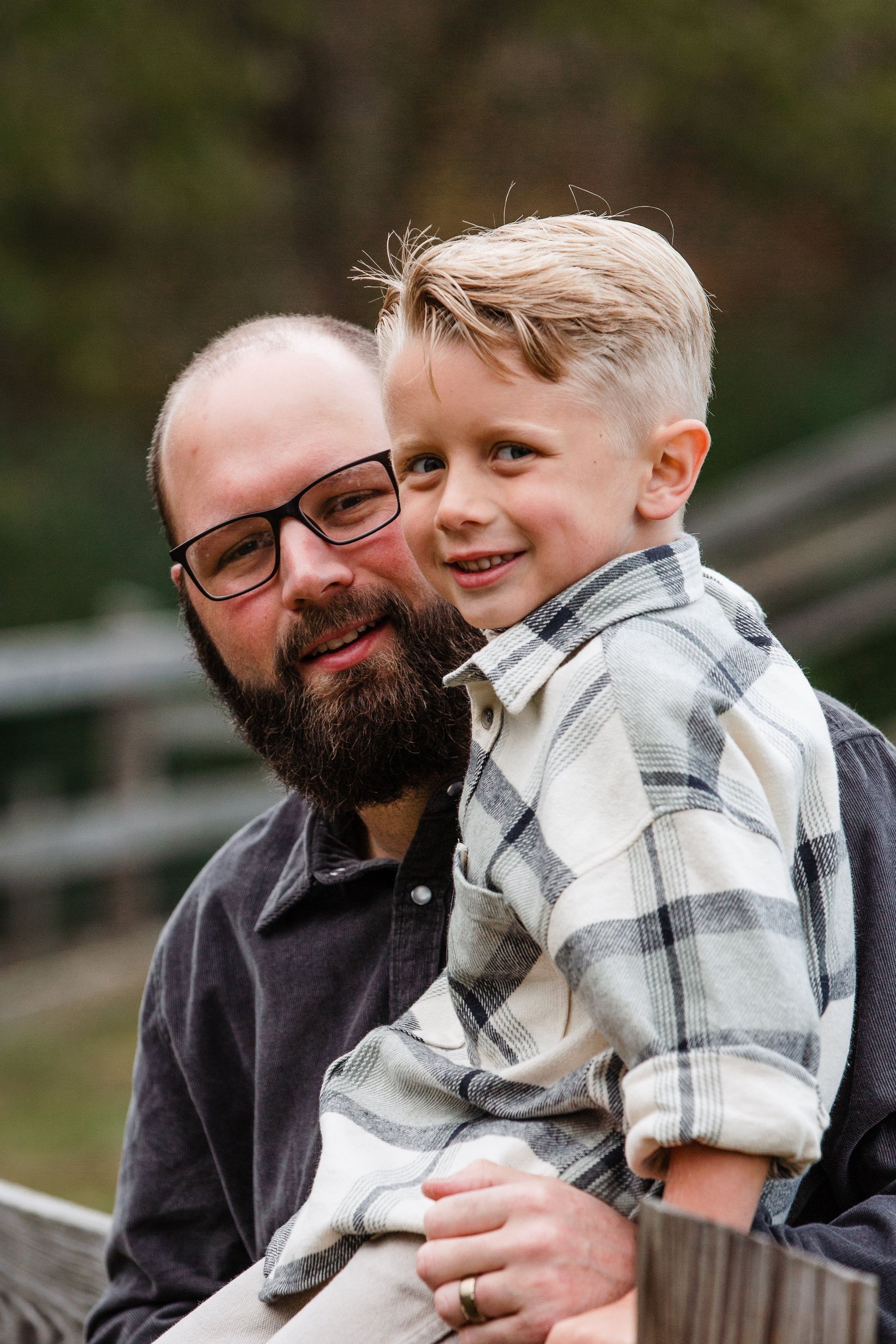 A man with a beard is holding a little boy in his arms.