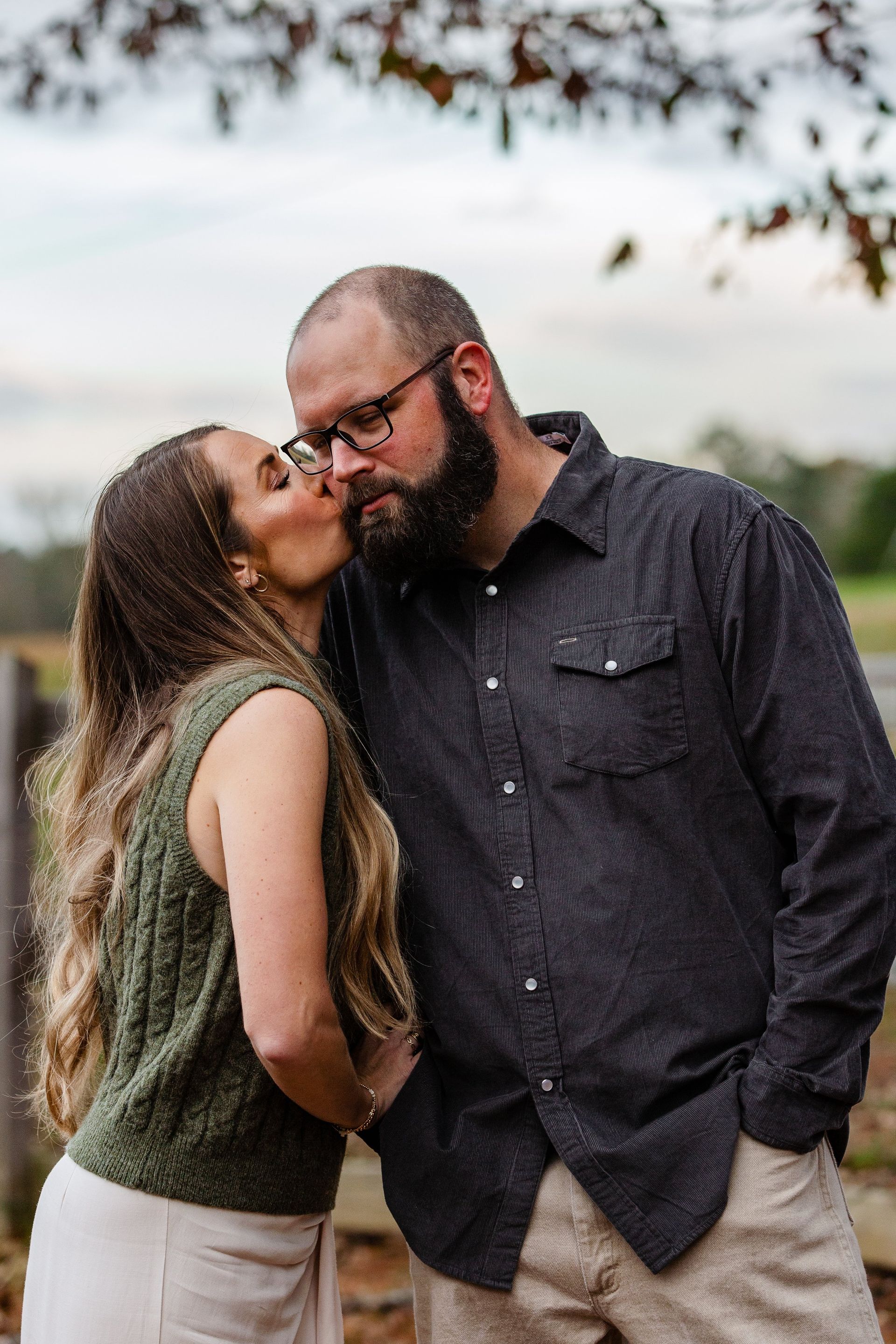 A woman is kissing a man on the cheek.
