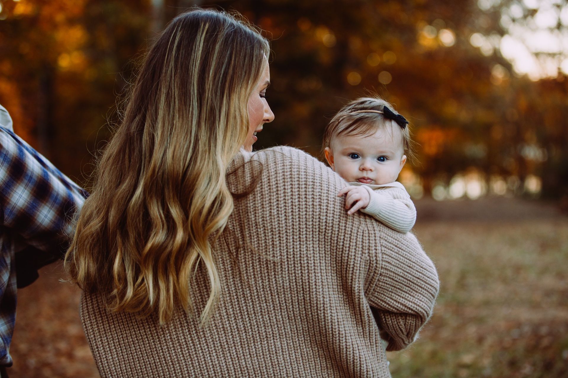 A woman is holding a baby in her arms in a field.