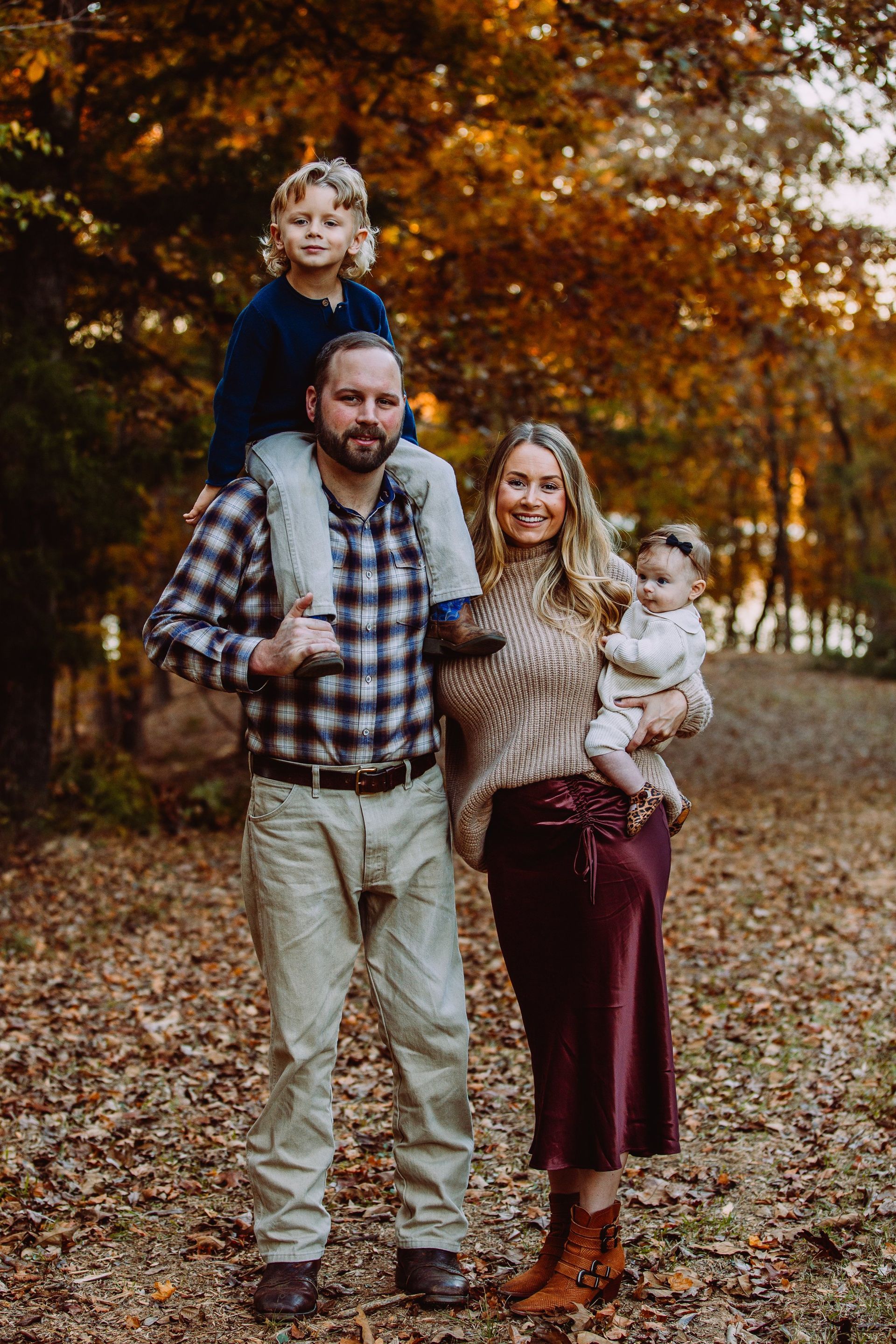 A family is posing for a picture in the woods.