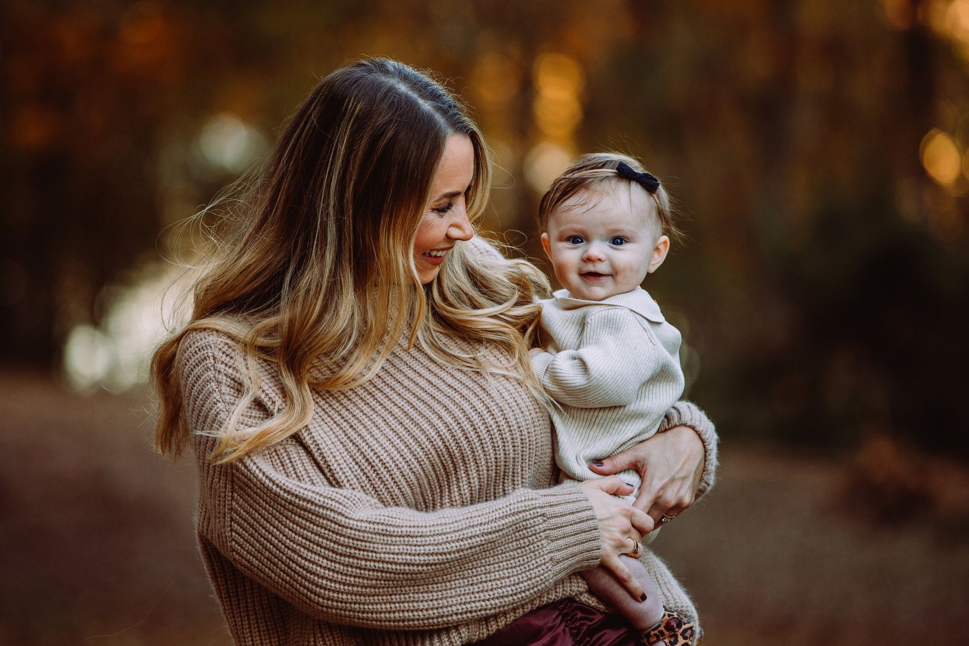 A woman is holding a baby in her arms in the woods.