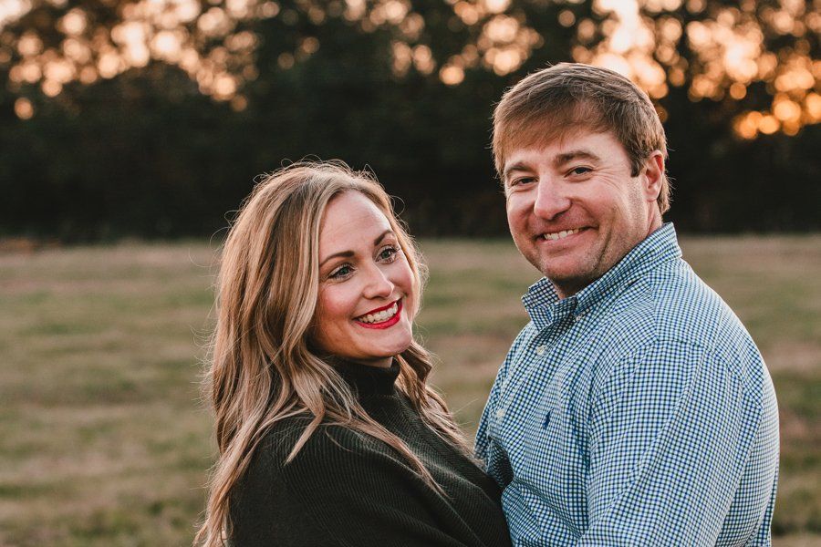 A man and a woman are standing next to each other in a field.