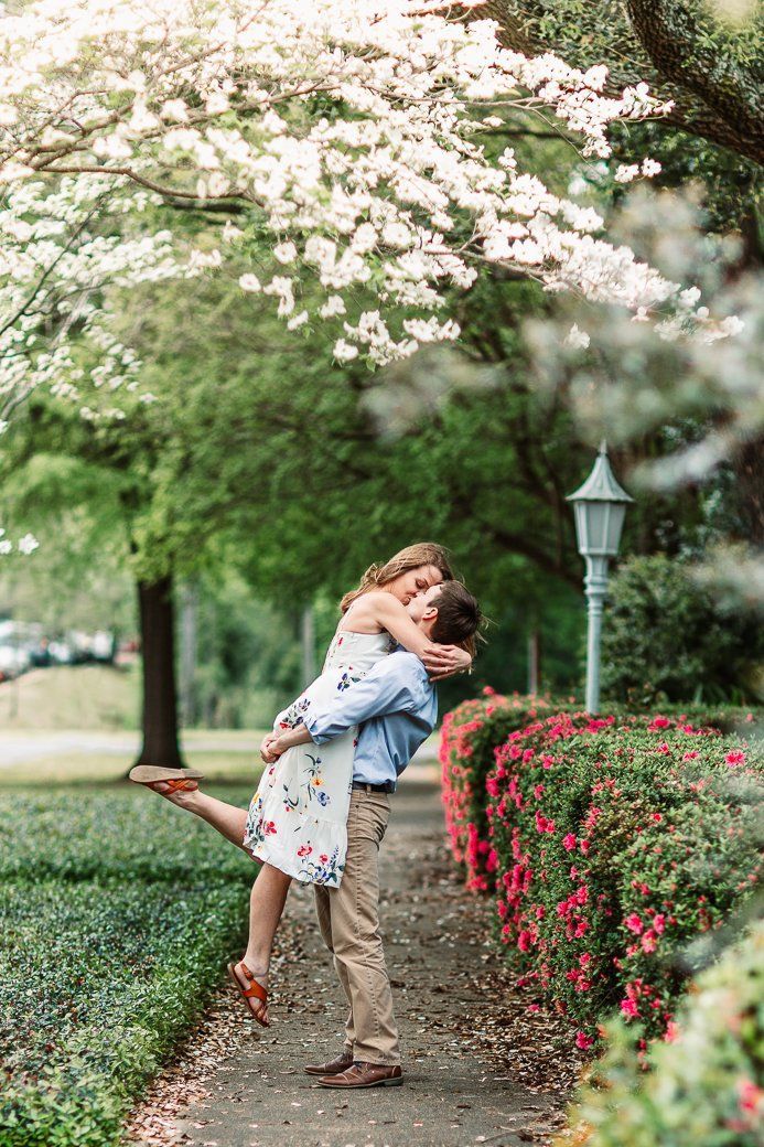 A man is holding a woman in his arms in a park.
