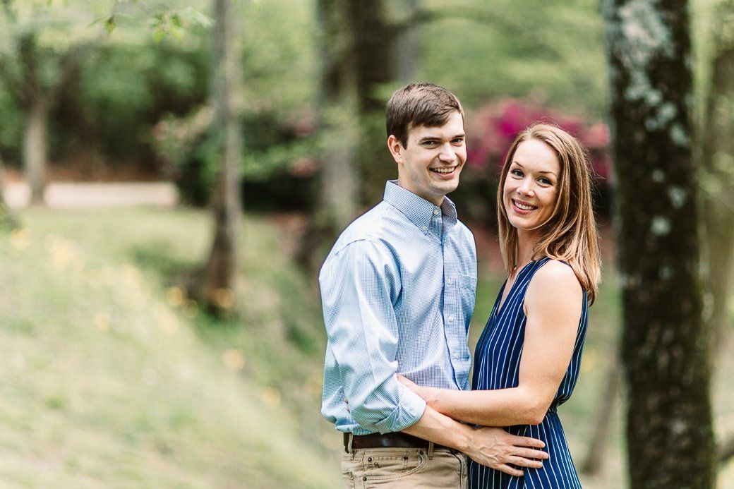 A man and a woman are standing next to each other in the woods.