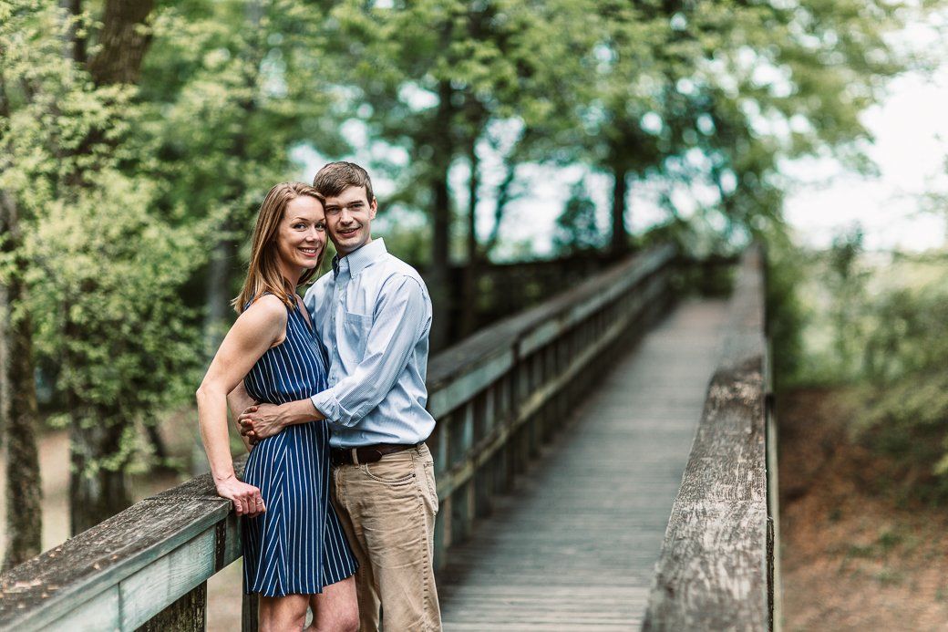 A man and a woman are standing on a wooden bridge.