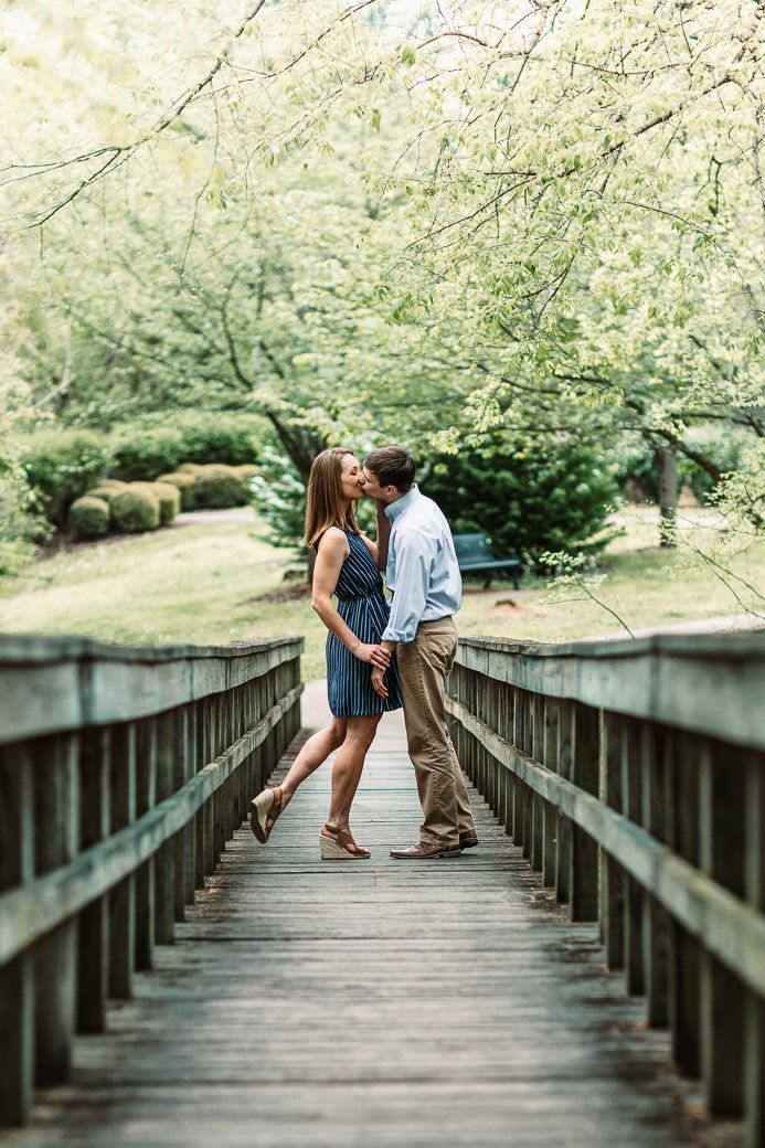 A man and a woman are kissing on a wooden bridge.