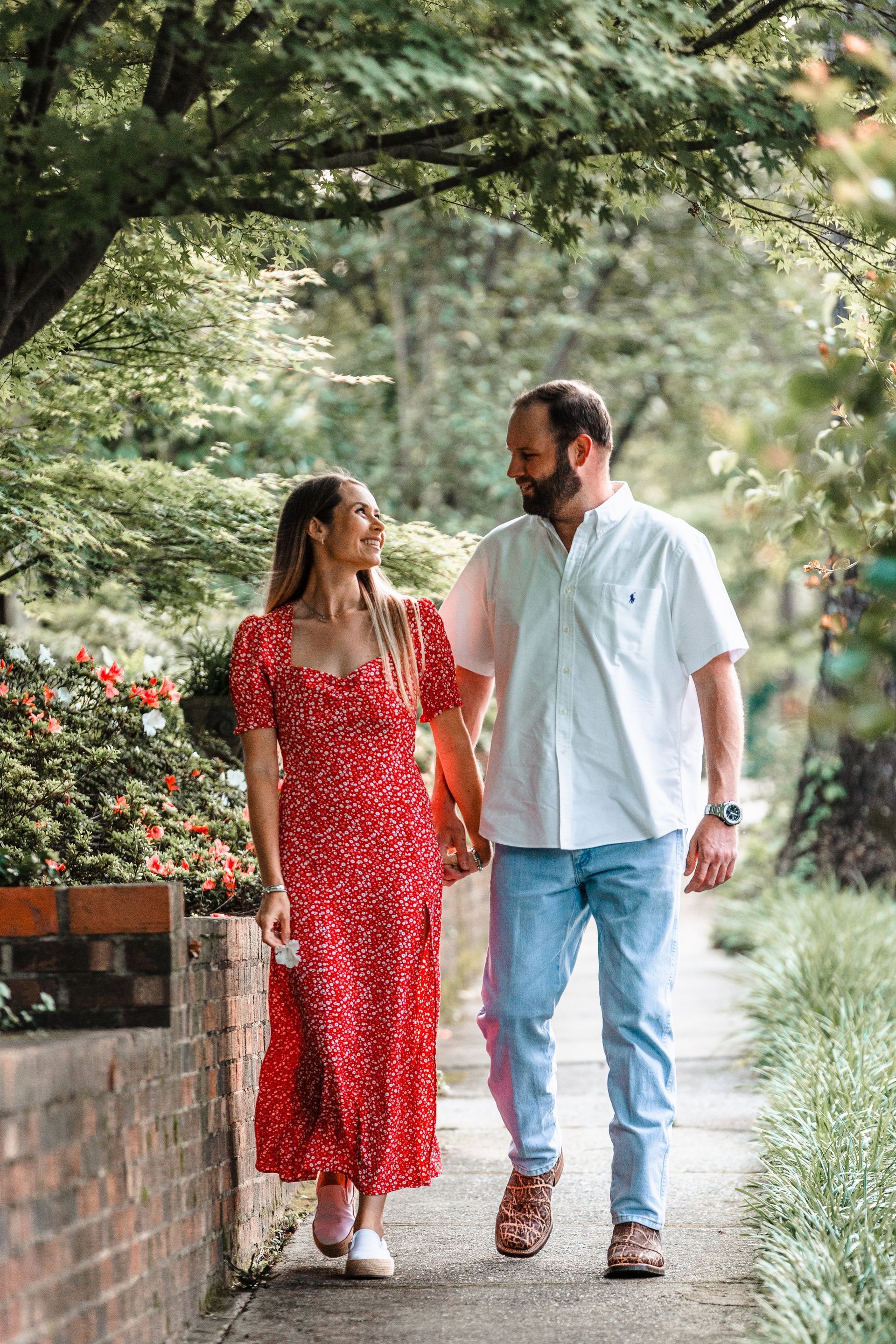 A man and a woman are walking down a sidewalk holding hands.