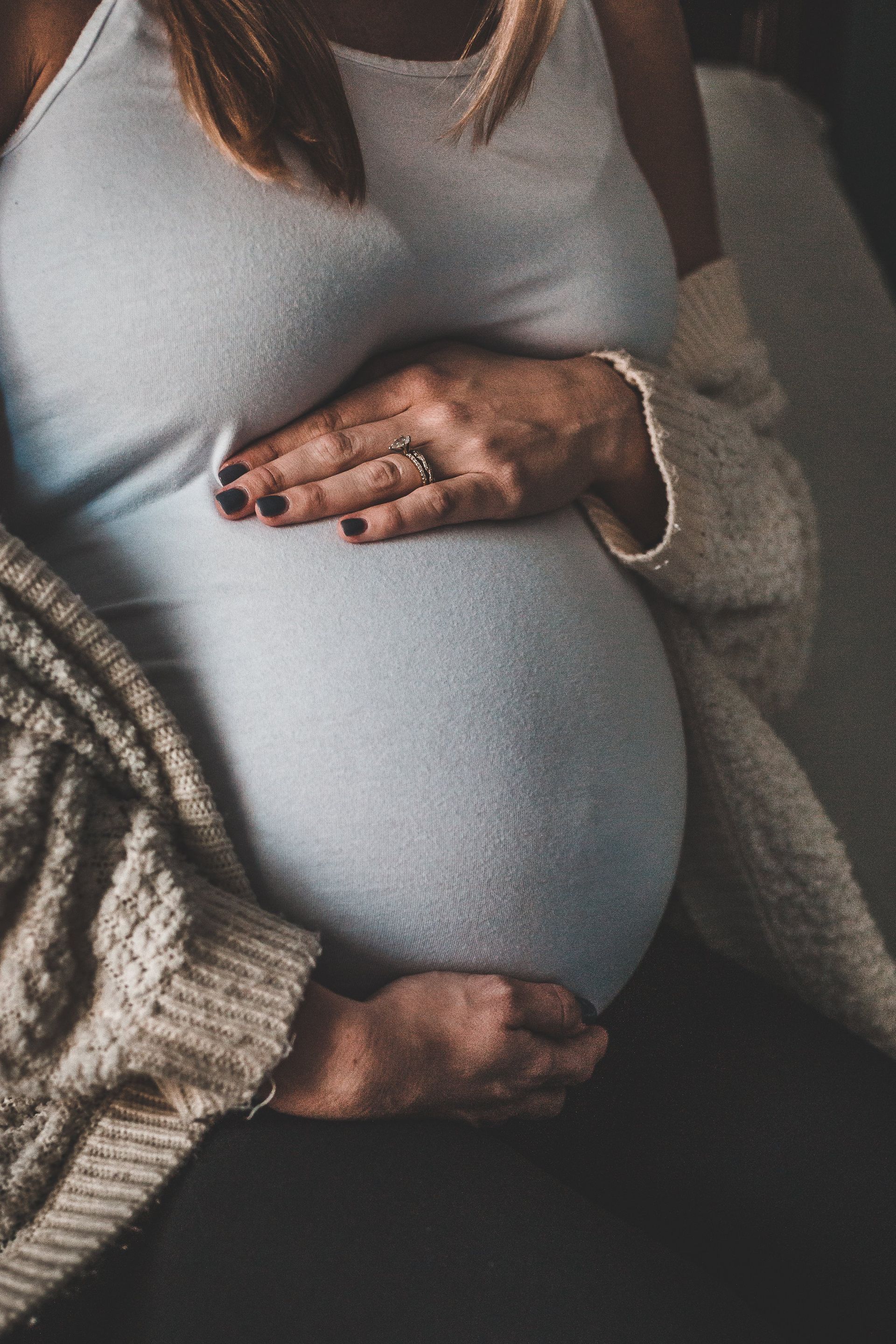 A pregnant woman is holding her belly with her hands.