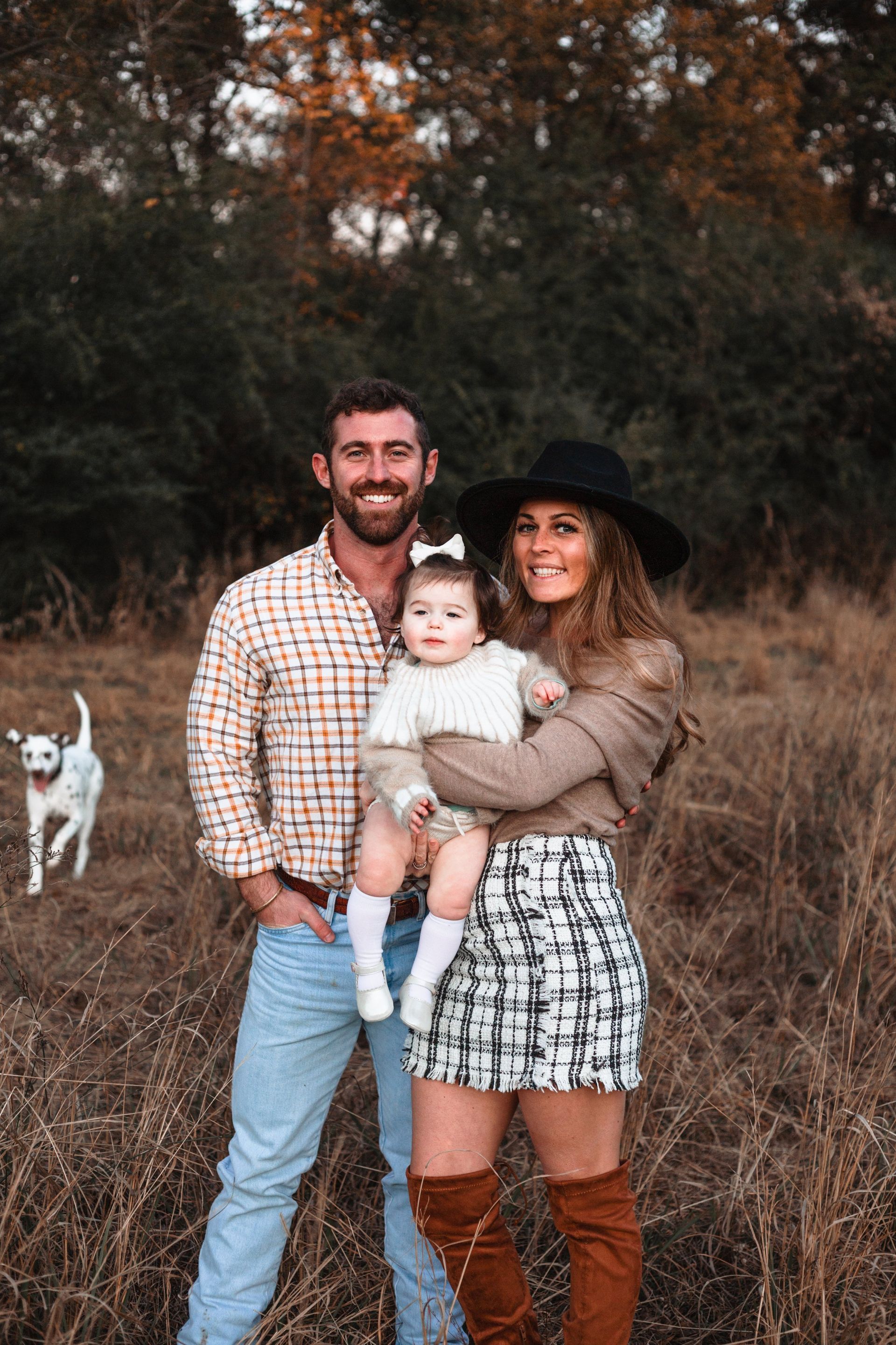 A family is posing for a picture in a field with two dogs.