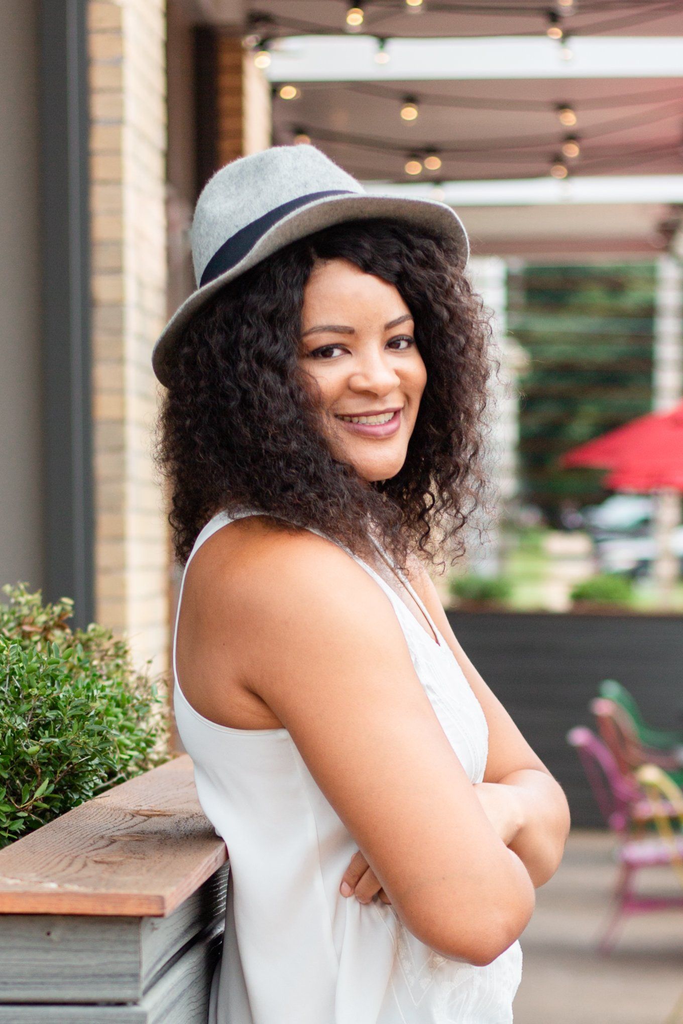 The woman is wearing a hat and a white tank top.