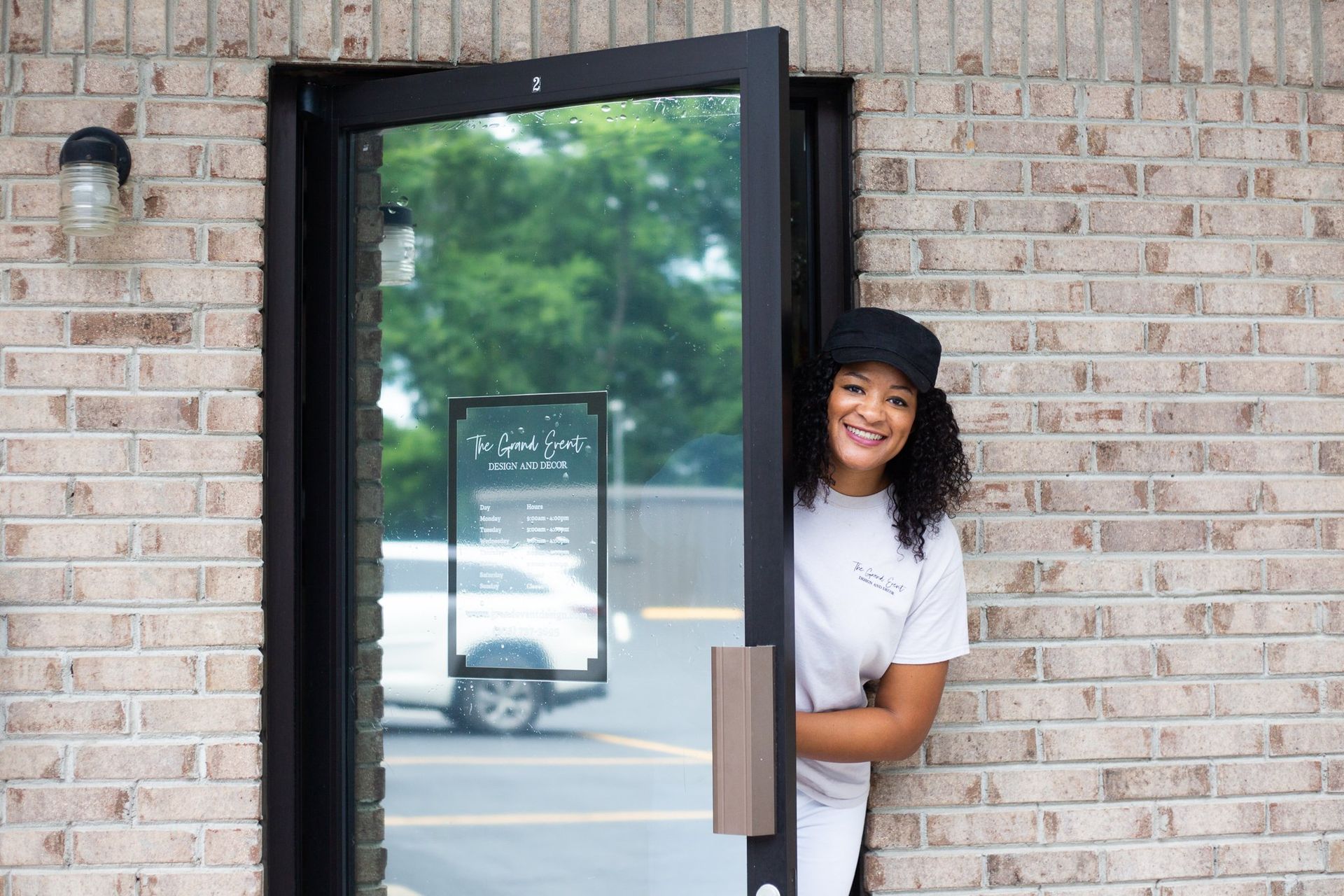 A woman is standing in the doorway of a brick building.