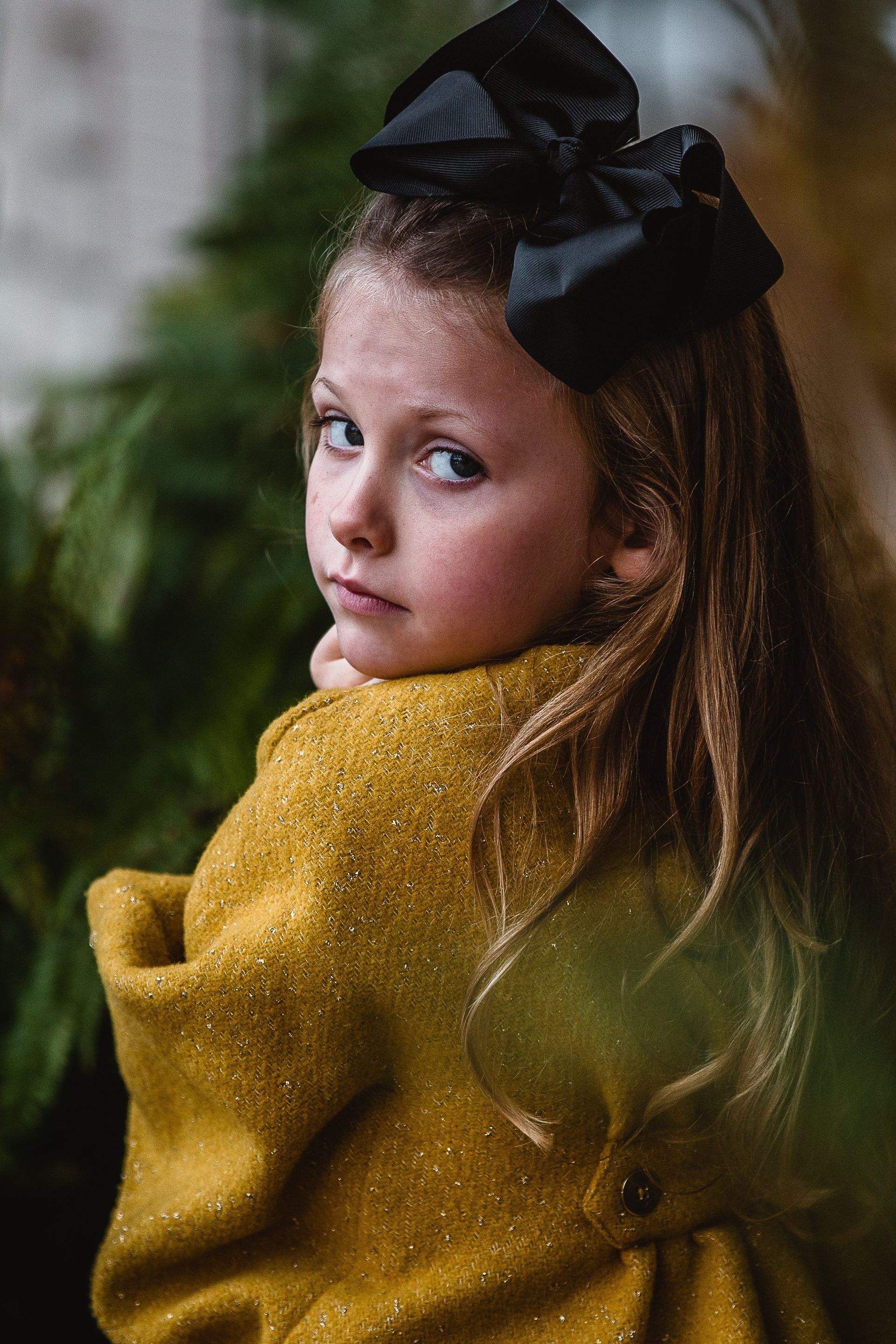 Young girl dressed in yellow looking over her shoulder.